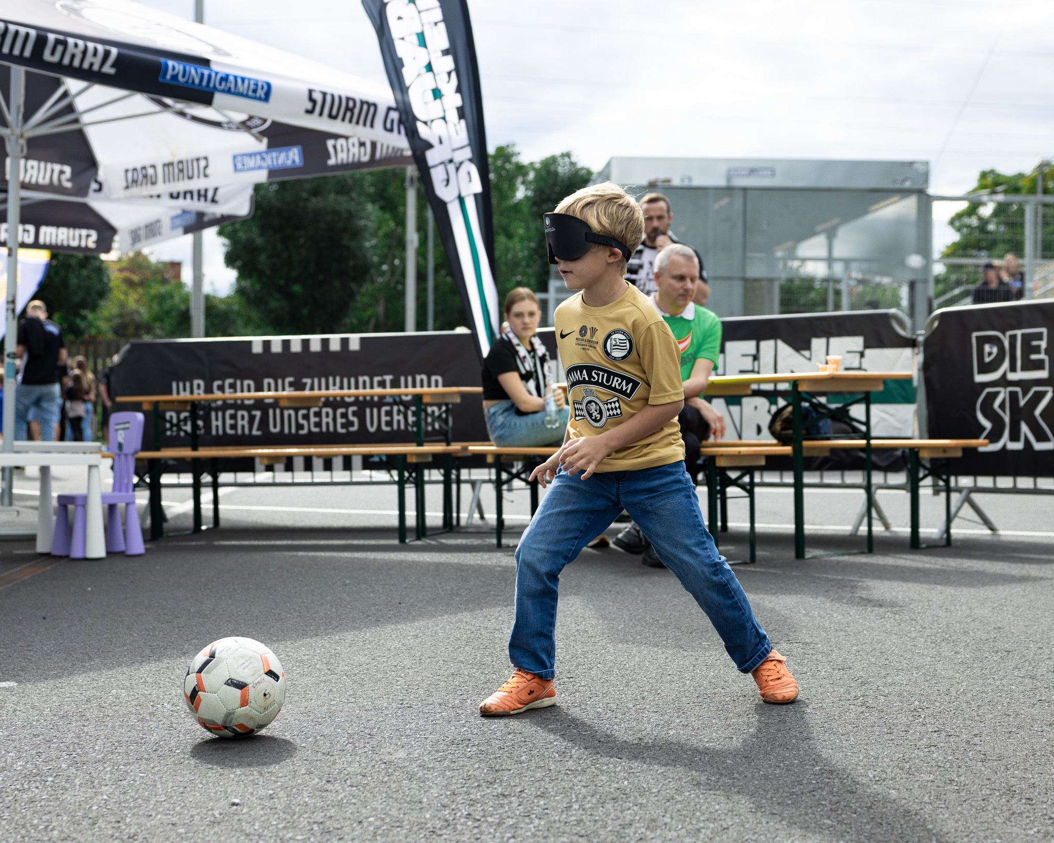 Kind mit Augenbinde spielt Blindenfußball.
