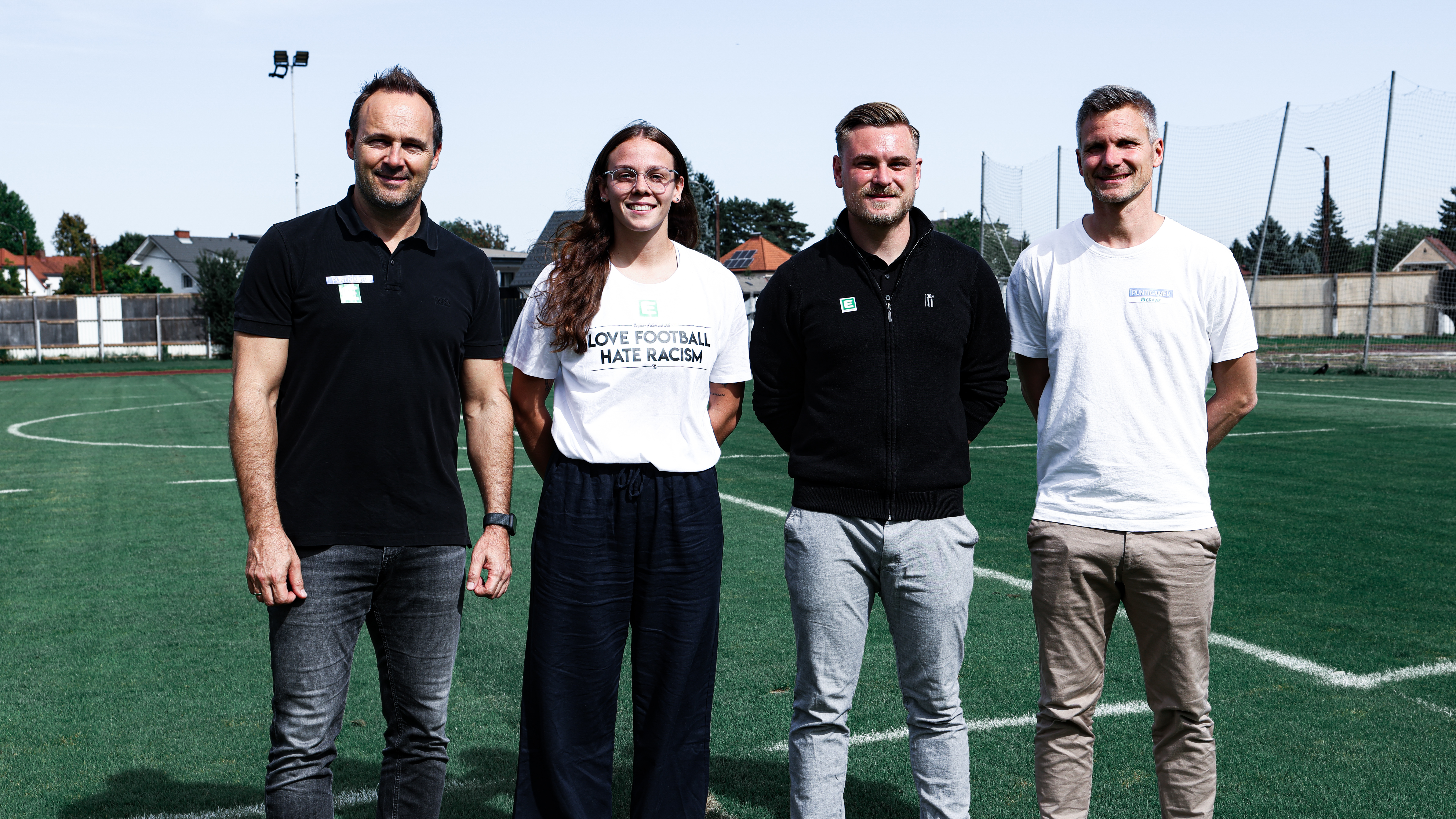 Drei Männer und eine Frau auf einem Fußballfeld
