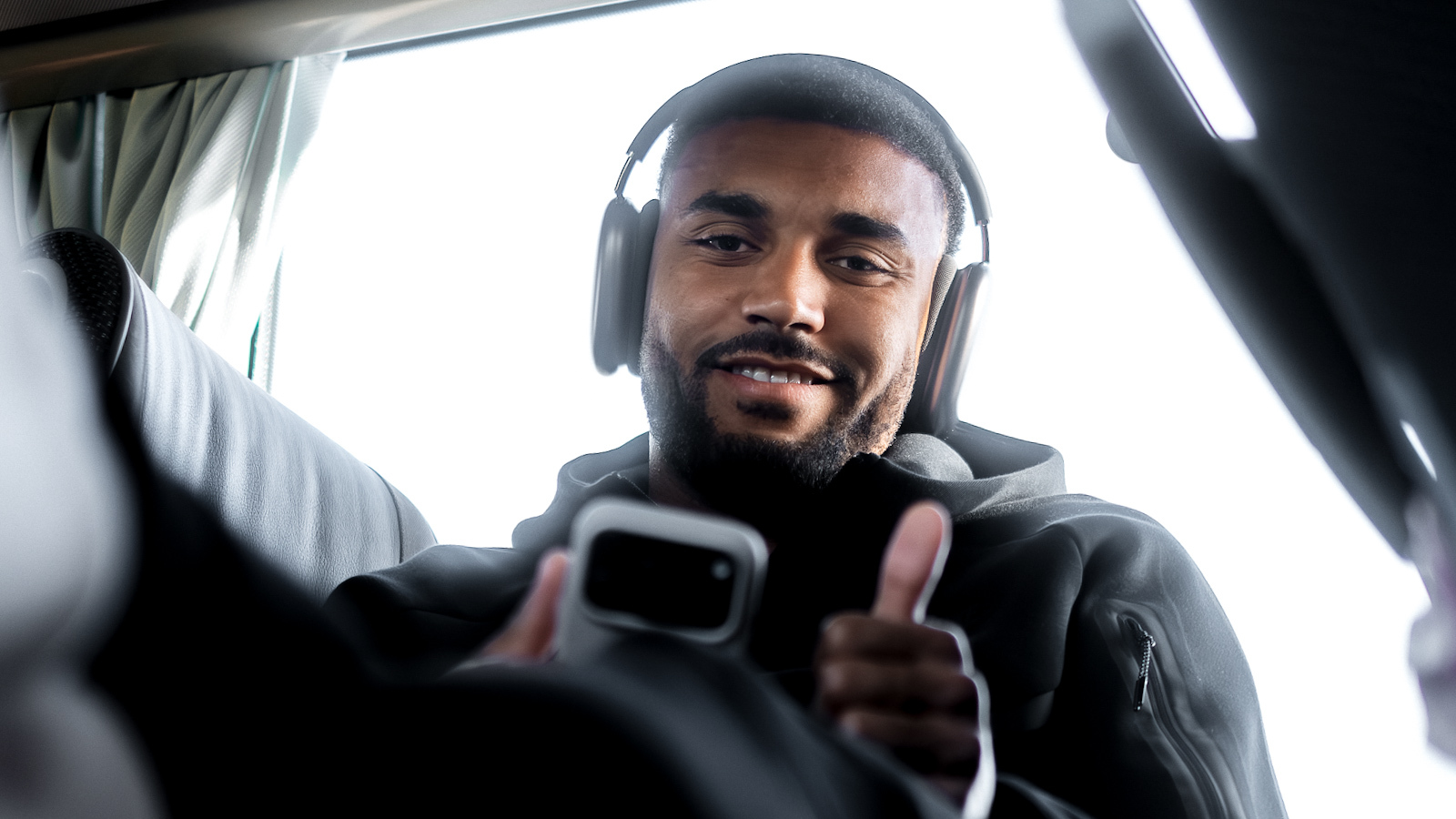 Ein Mann sitzt im Bus und hört mit Kopfhörer Musik