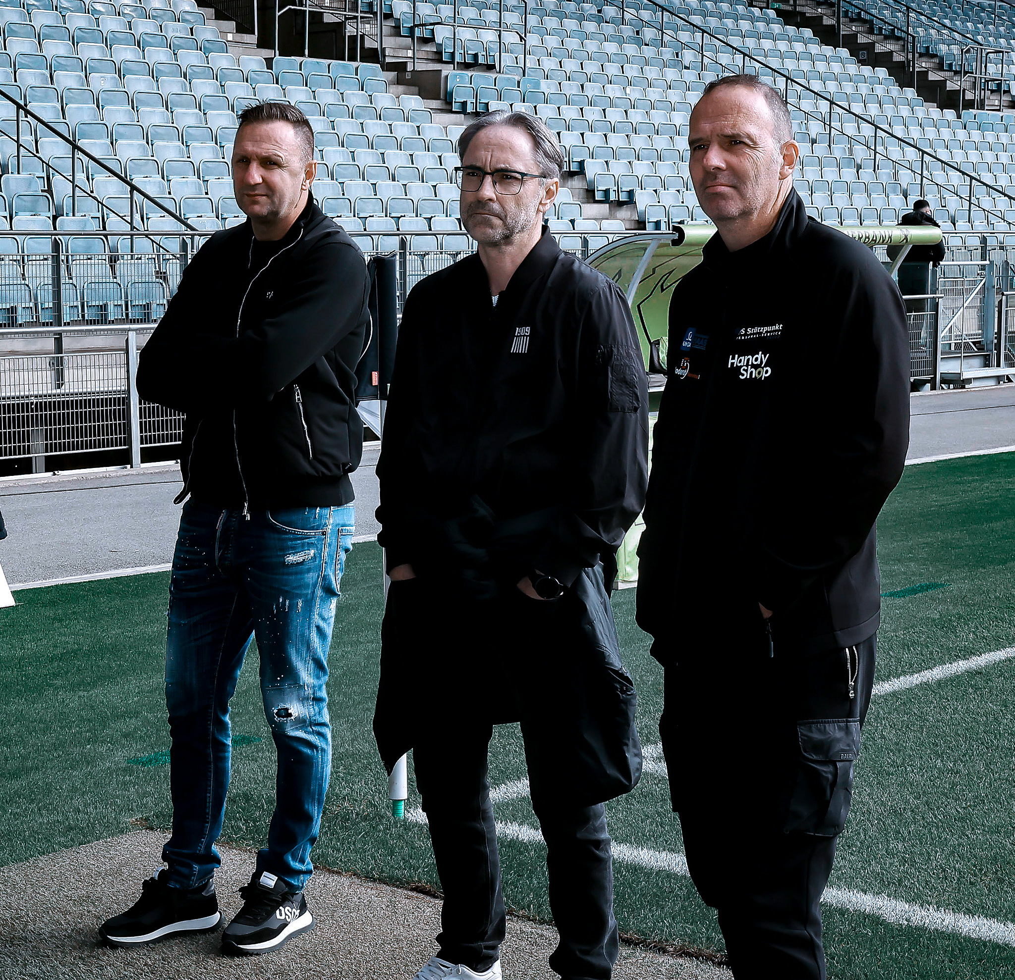 Drei stehen Männer im Stadion