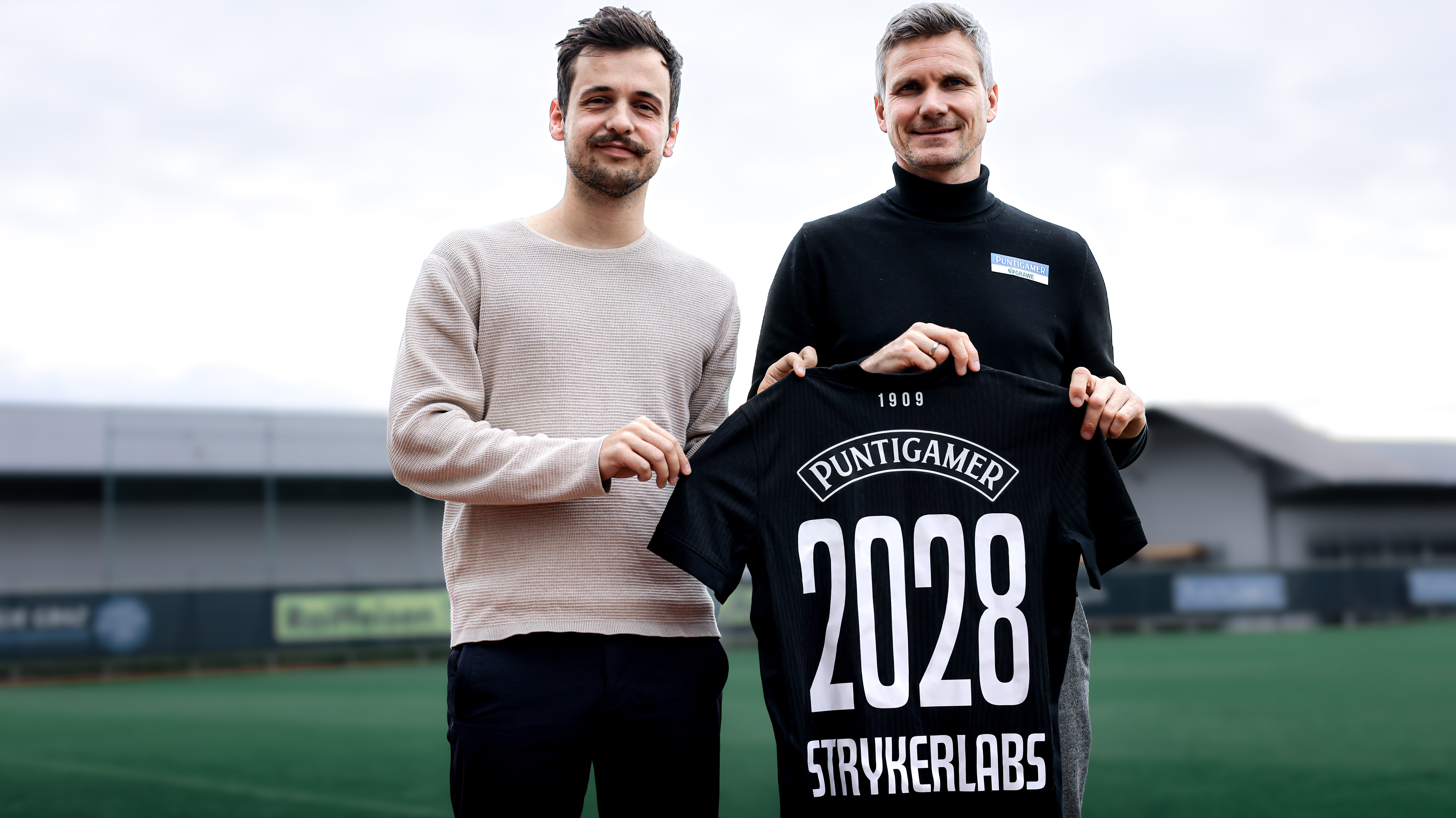 Zwei Männer halten ein Trikot hoch