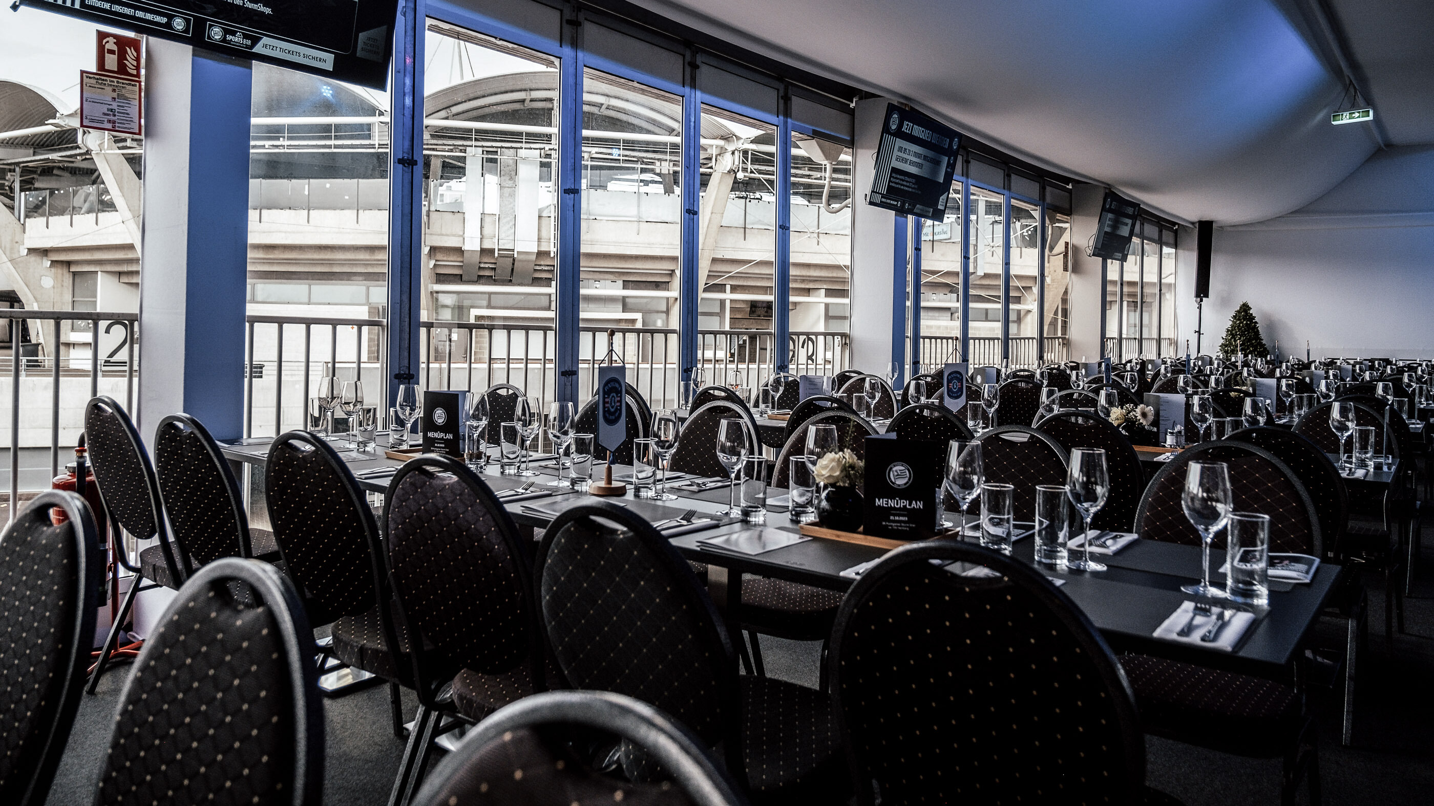 Viele Sessel und Tische in einem Raum mit großen Fenstern