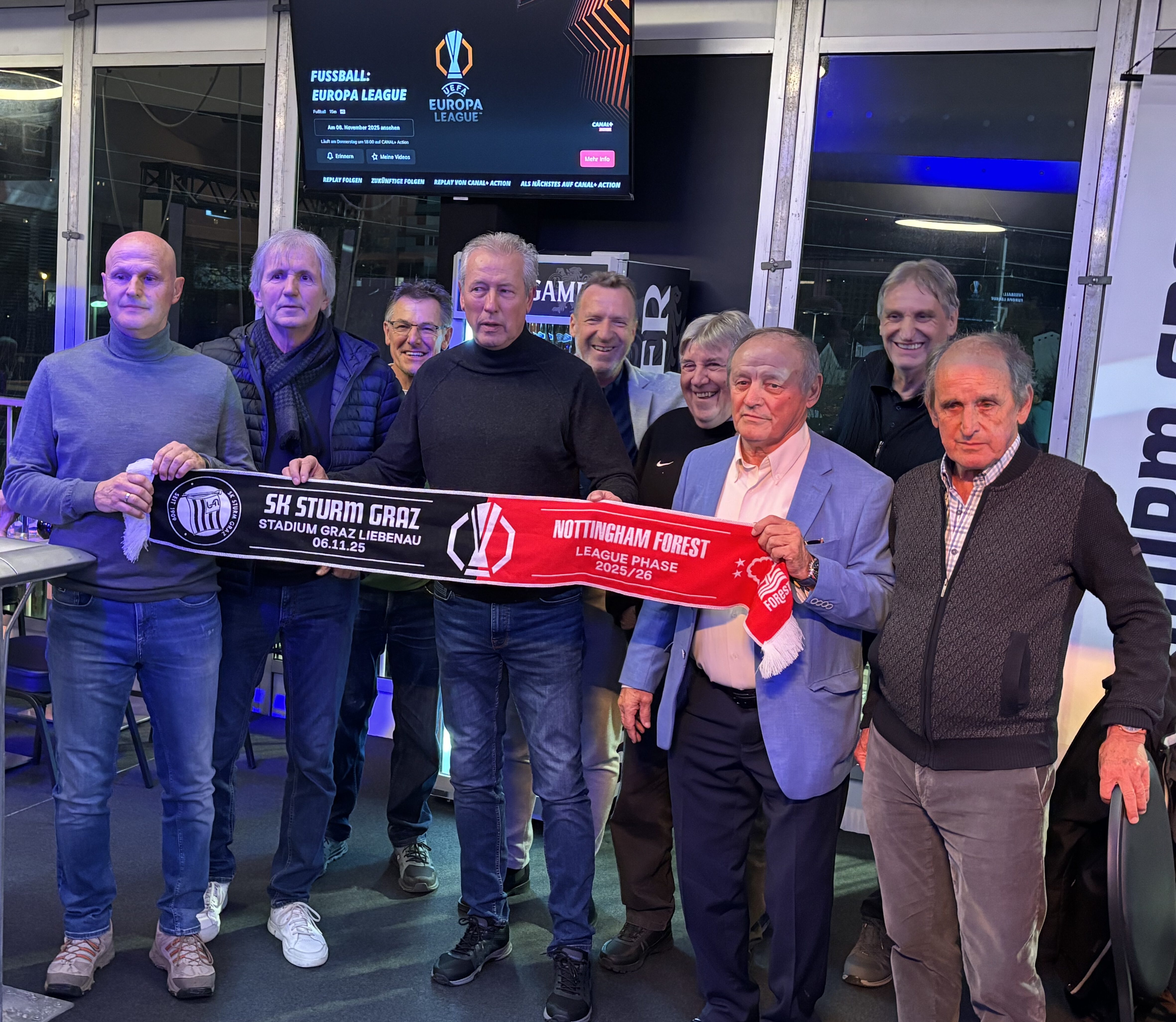 Neun Männer mit einem Fanschal.