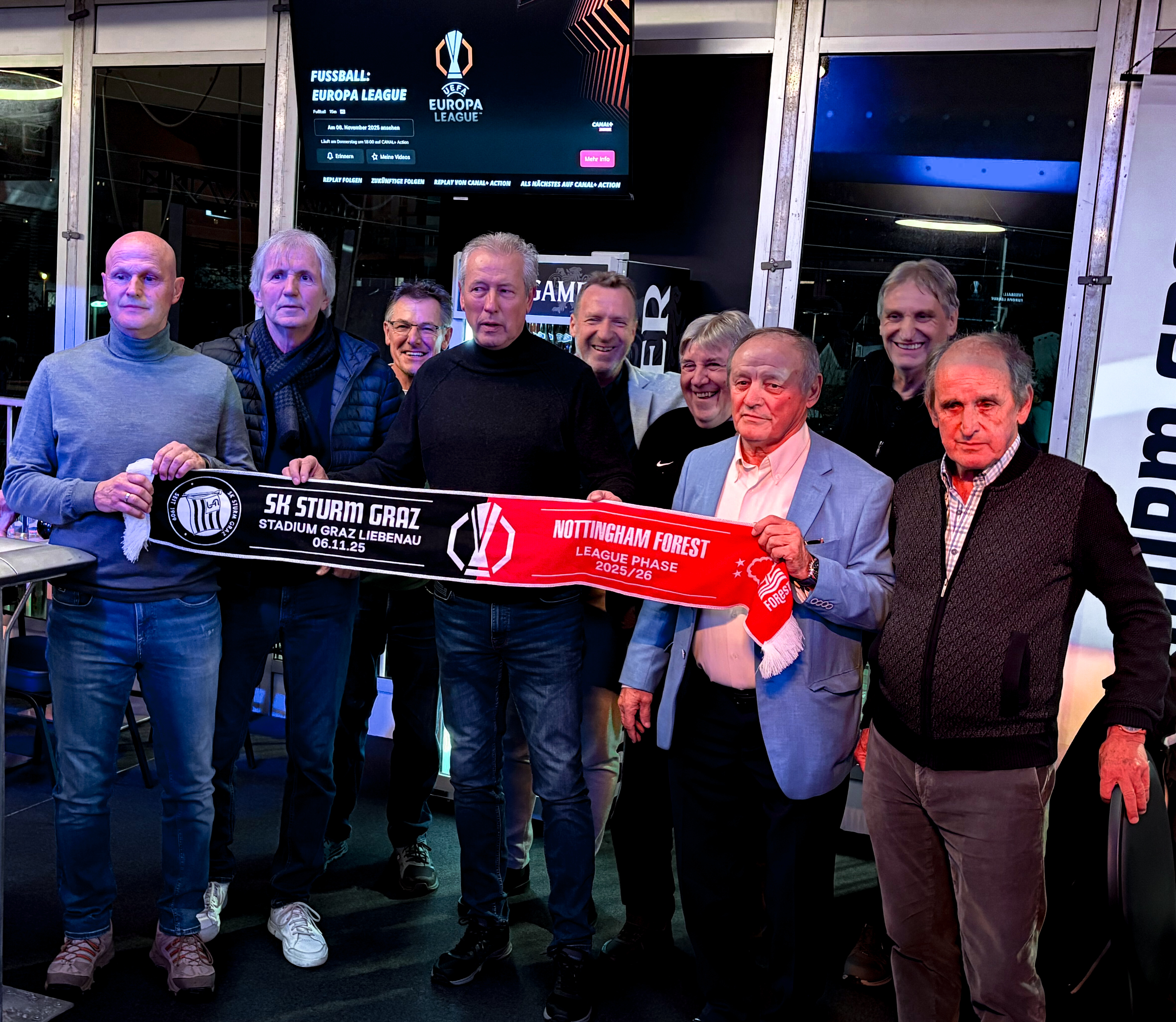 Neun Männer mit einem Fanschal.