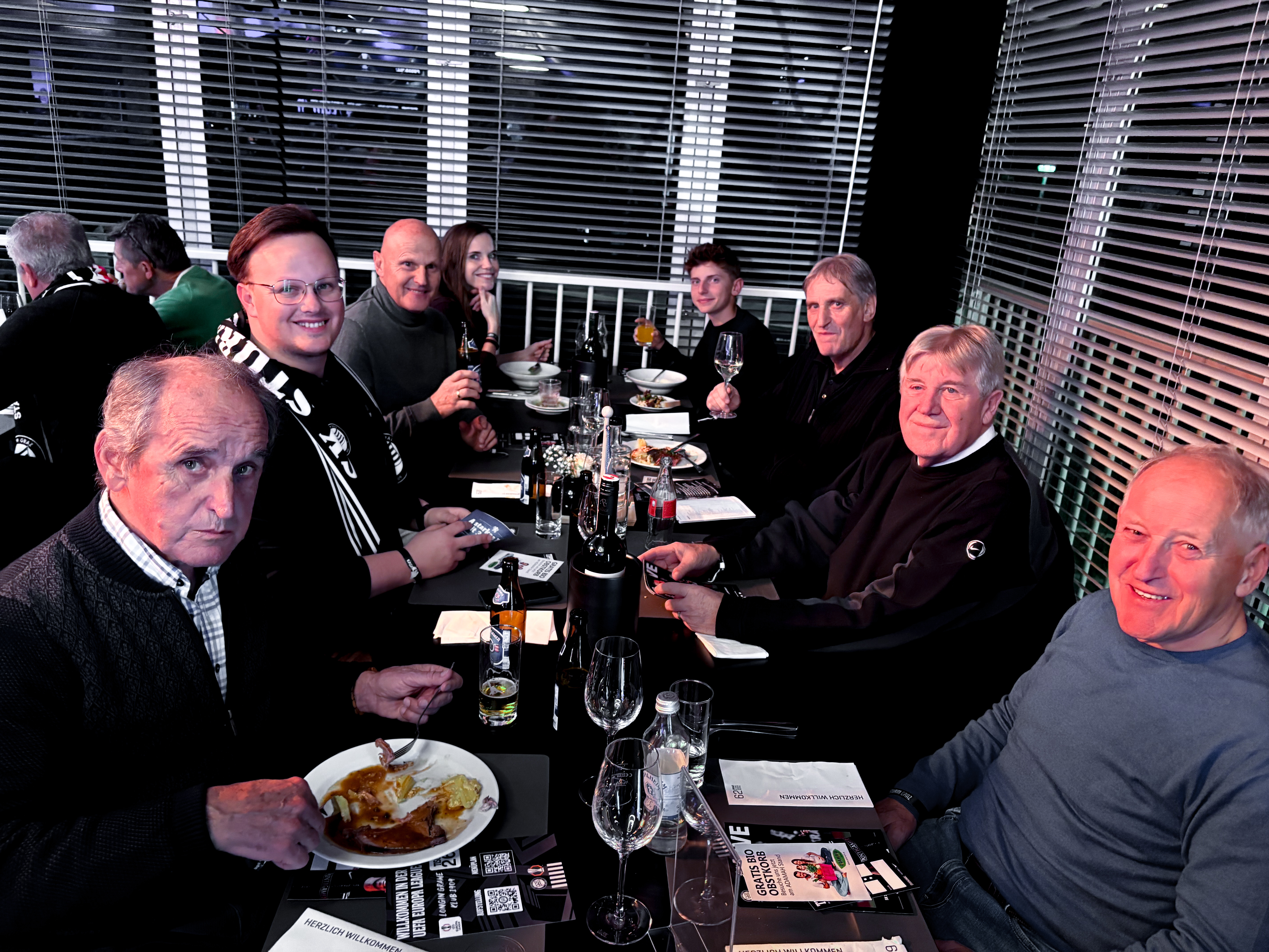 Acht Personen an einem Tisch beim Essen.