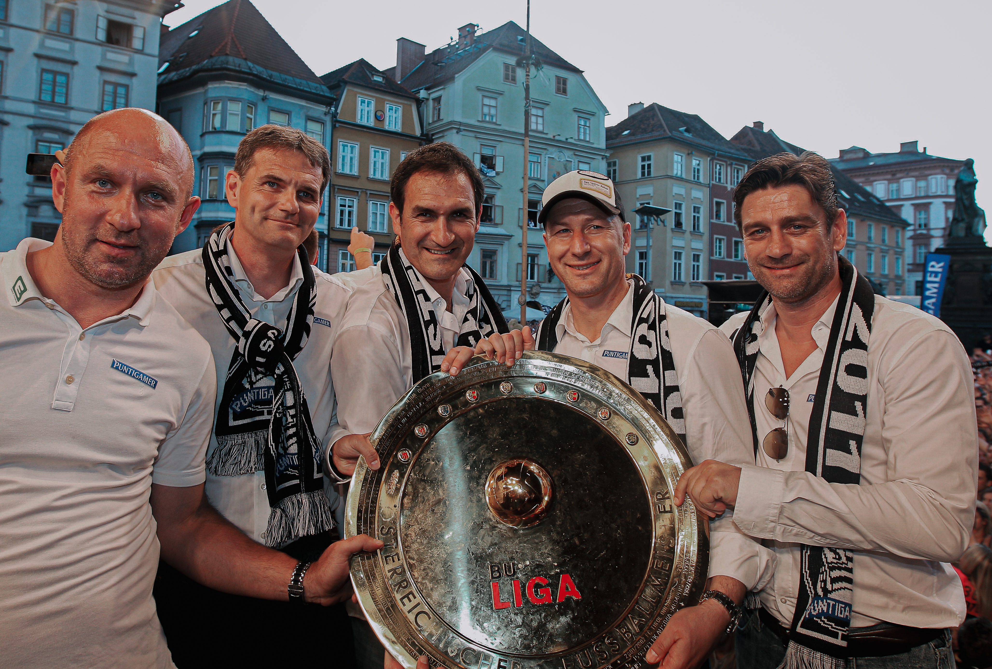 Fünf Männer halten eine Trophäe.