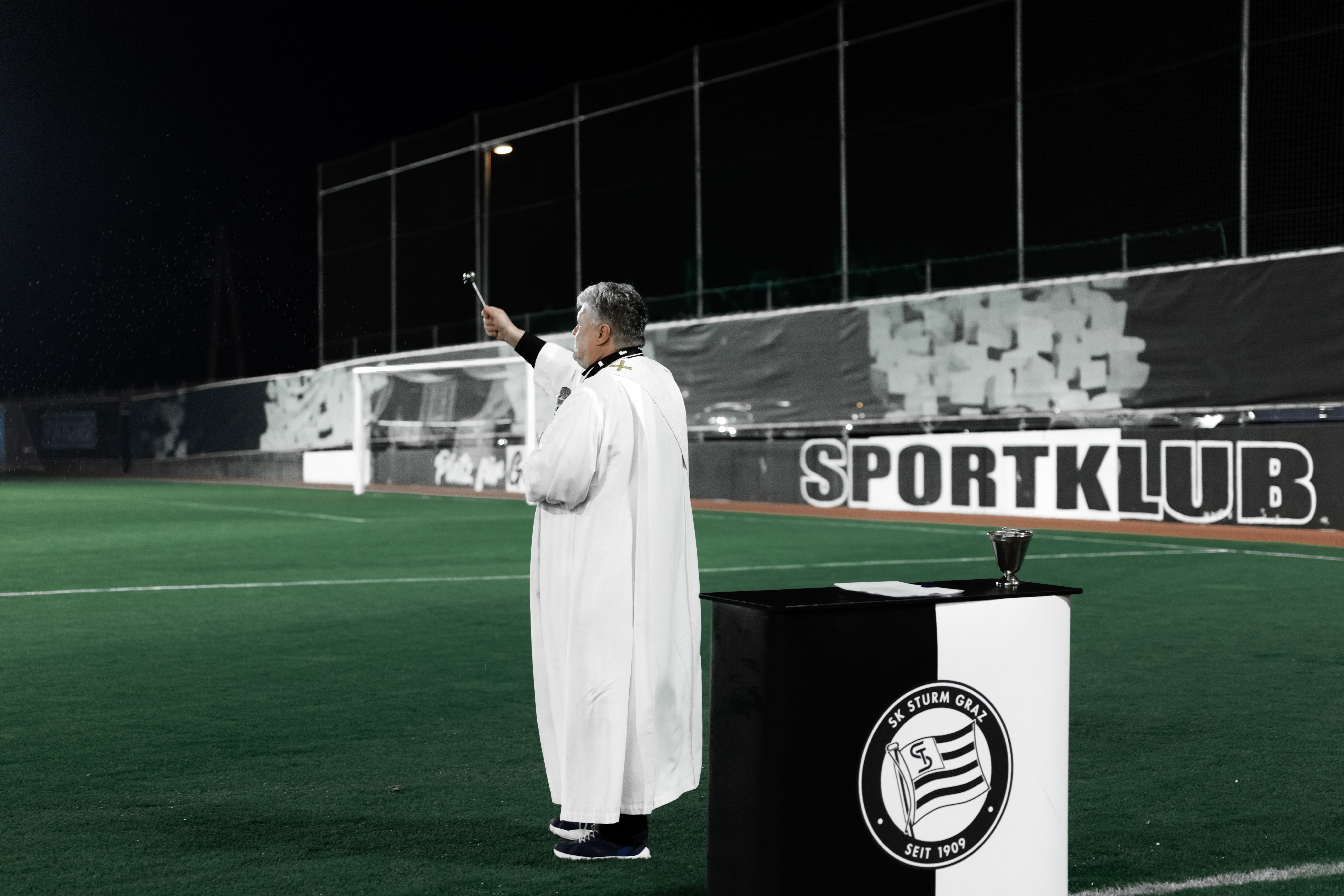 Ein Pfarrer weiht einen Fußballplatz