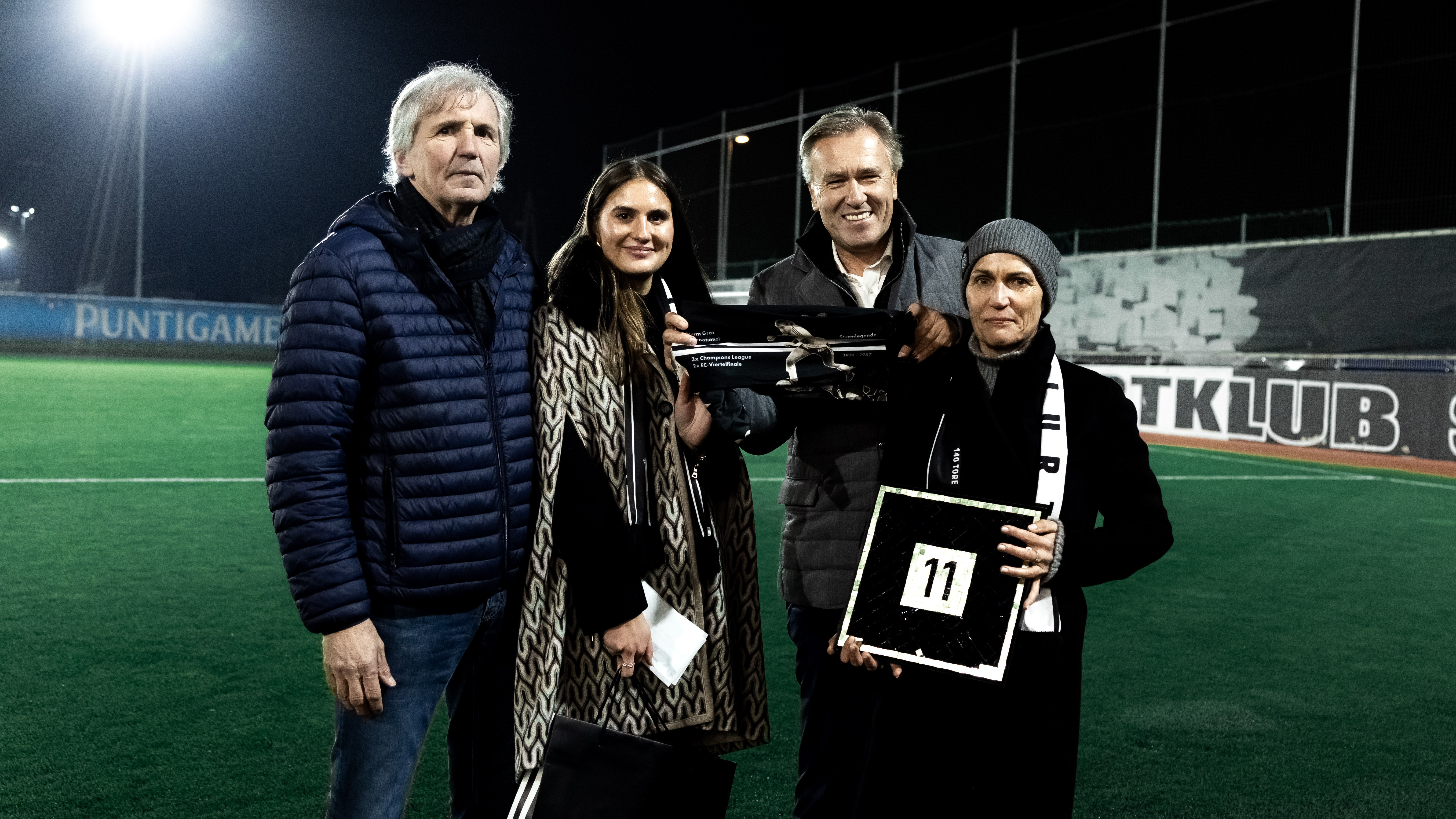 Zwei Männer und zwei Frauen halten einen Schal und ein Bild hoch