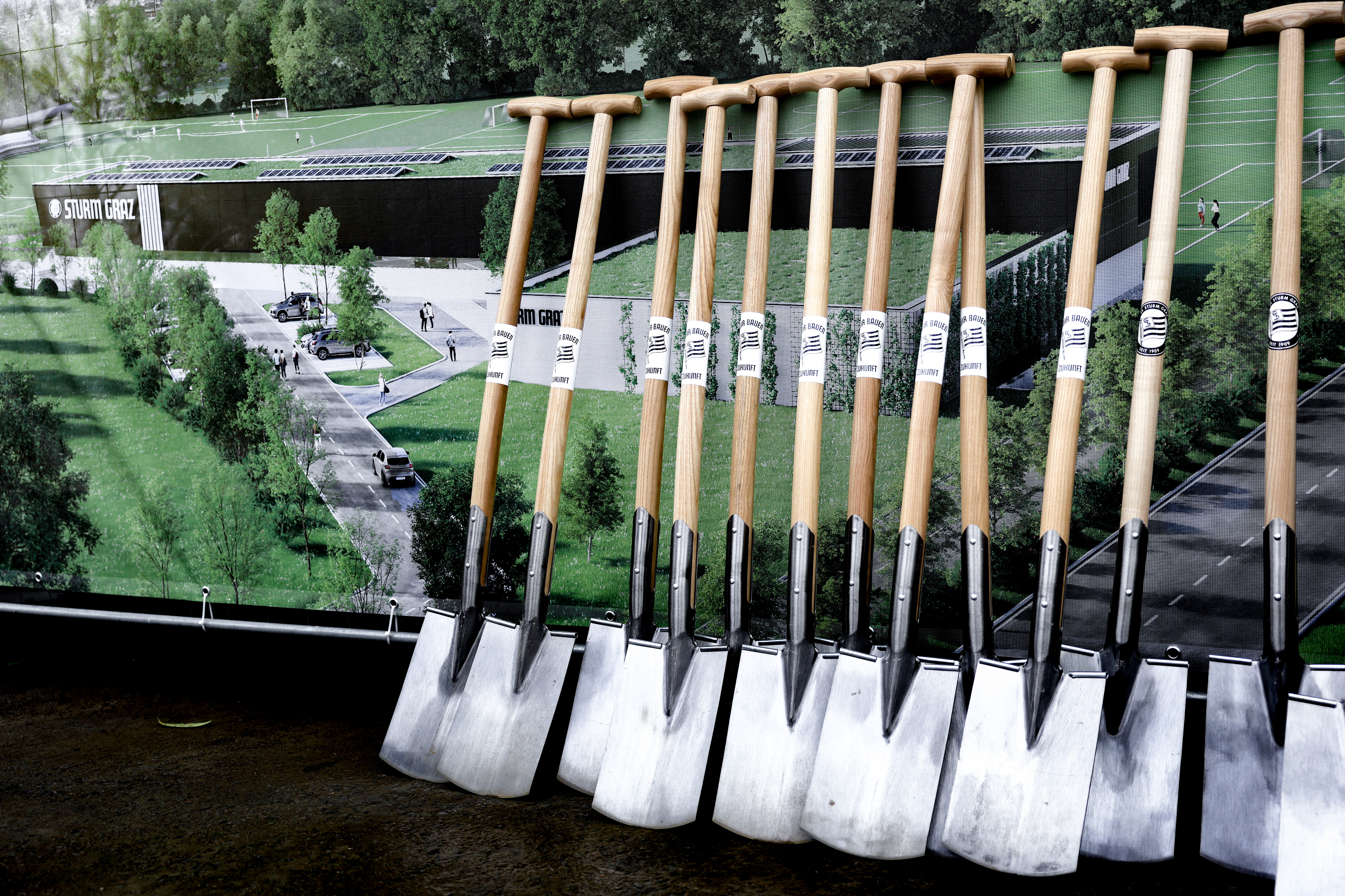 Schaufeln vor einem Bild des Trainingszentrums Puntigam