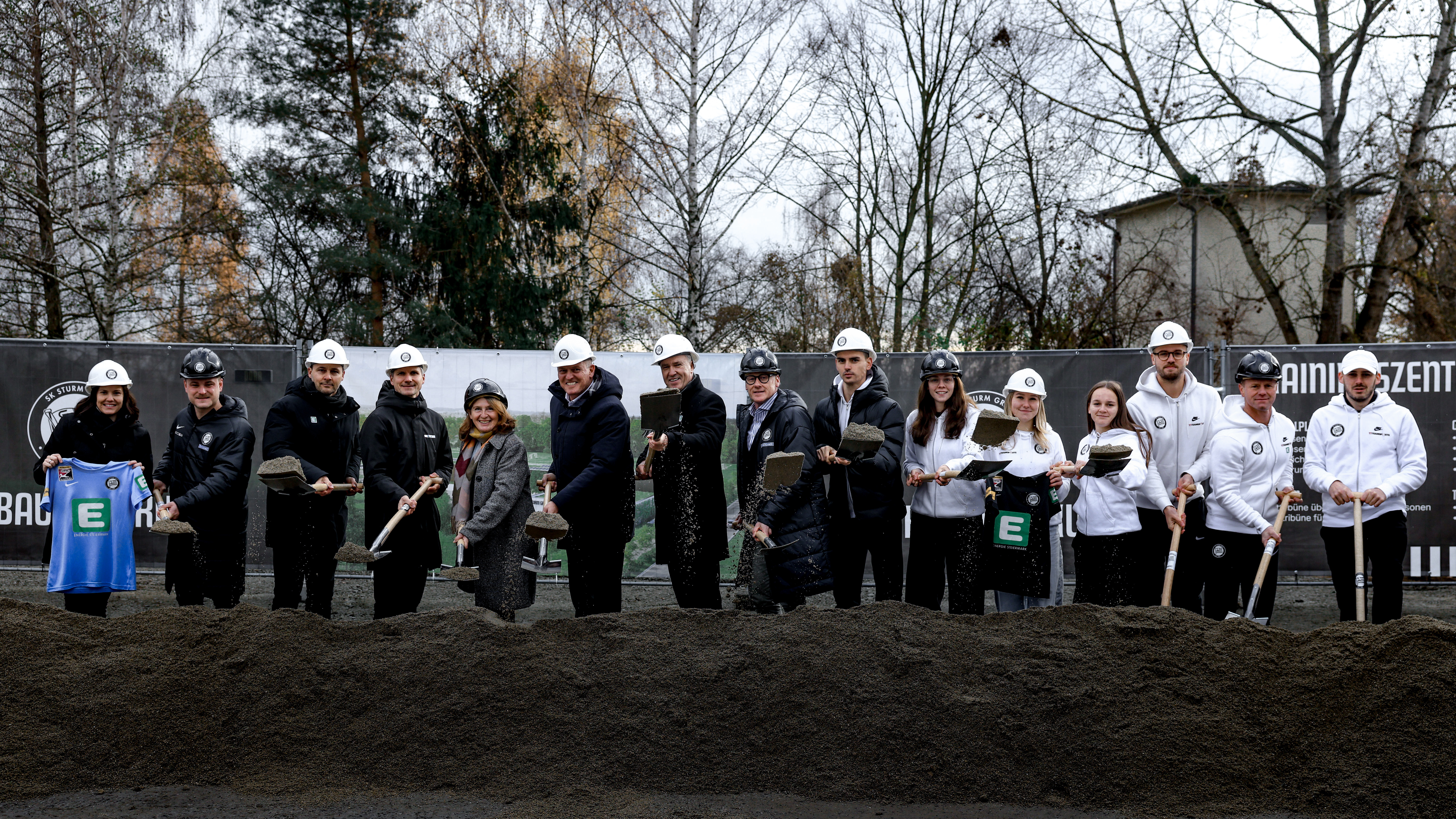 Eine Gruppe an Personen mit Bauhelmen und Schaufeln