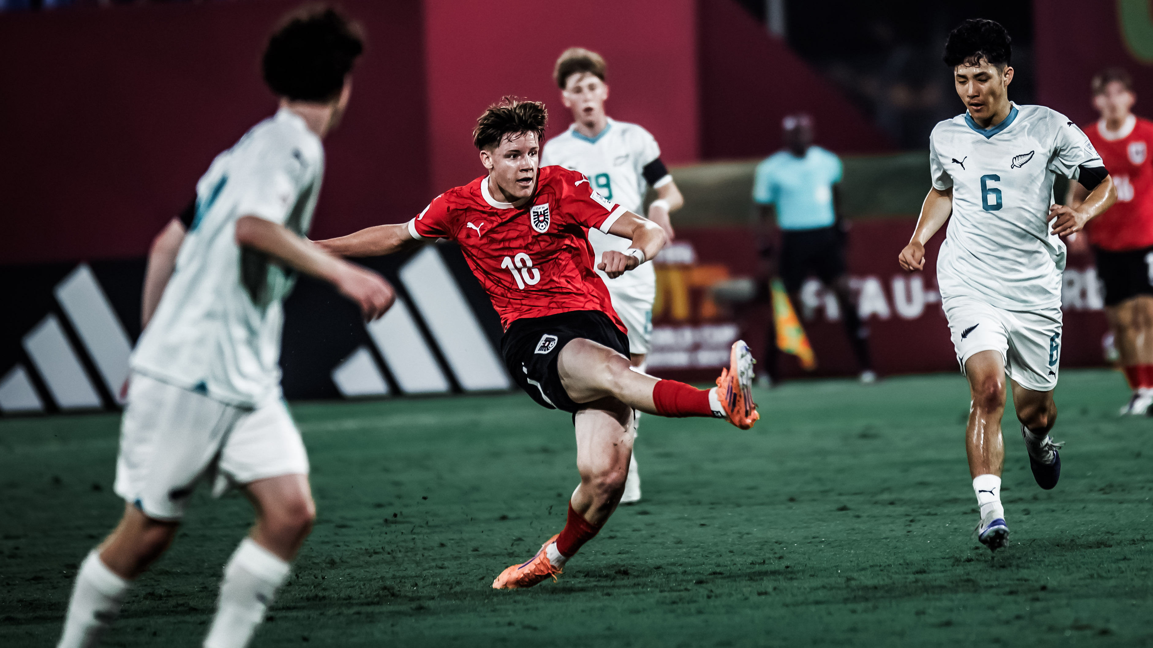 Ein Spieler in einem roten Trikot umgeben von drei mit in weißen Trikots