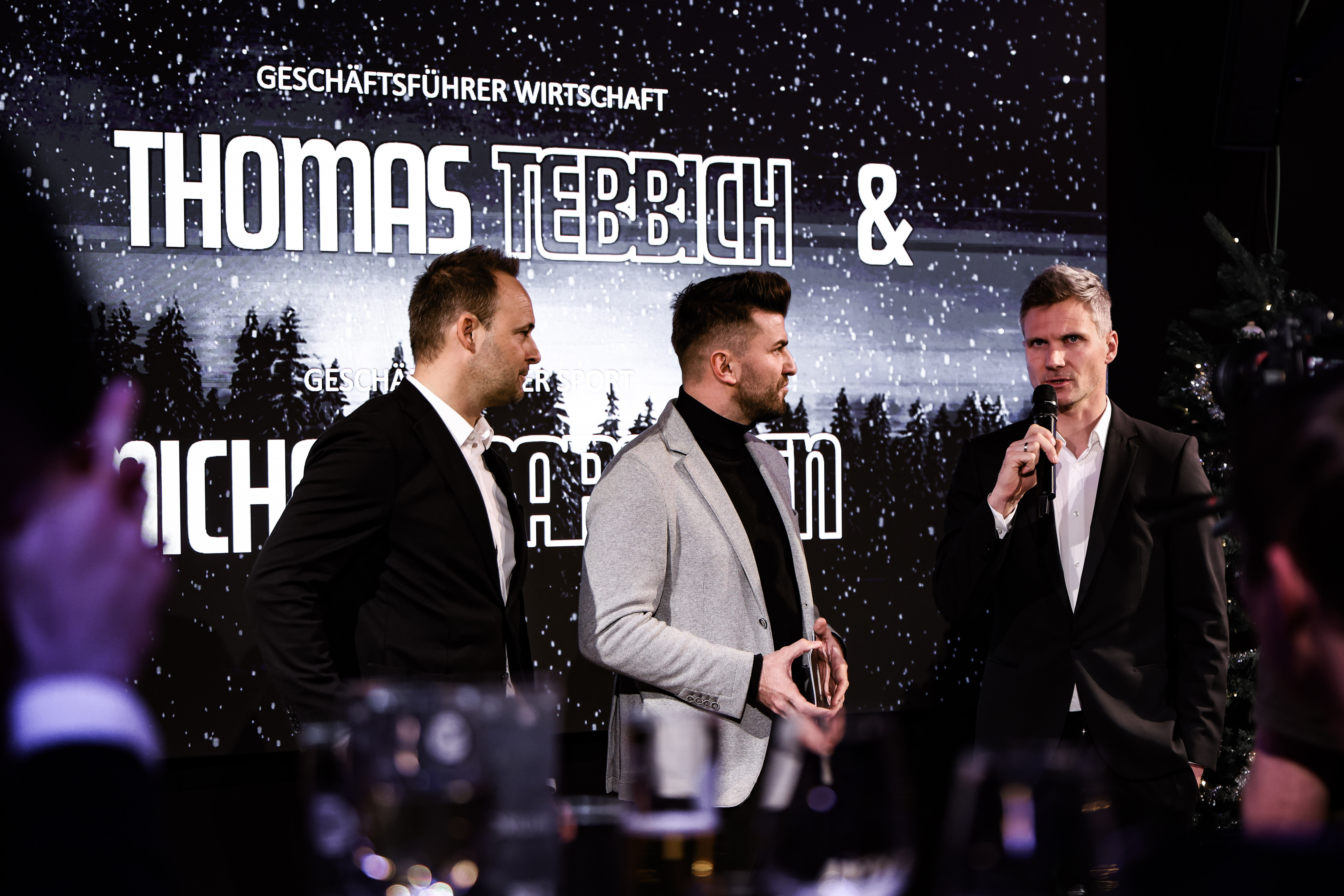 Drei Männer vor einer Leinwand