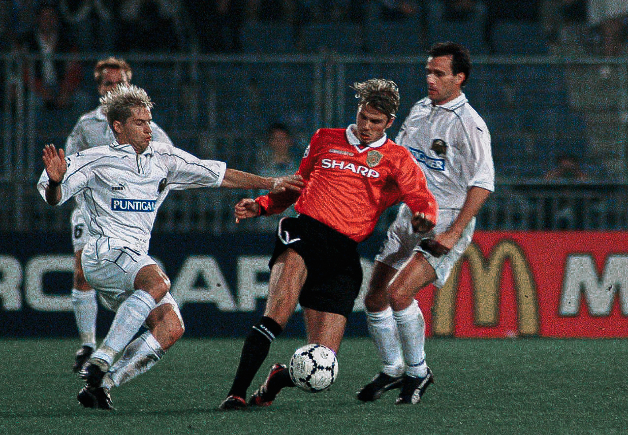 Eine Gruppe Fußballer, drei in Weiß, einer in Rot.