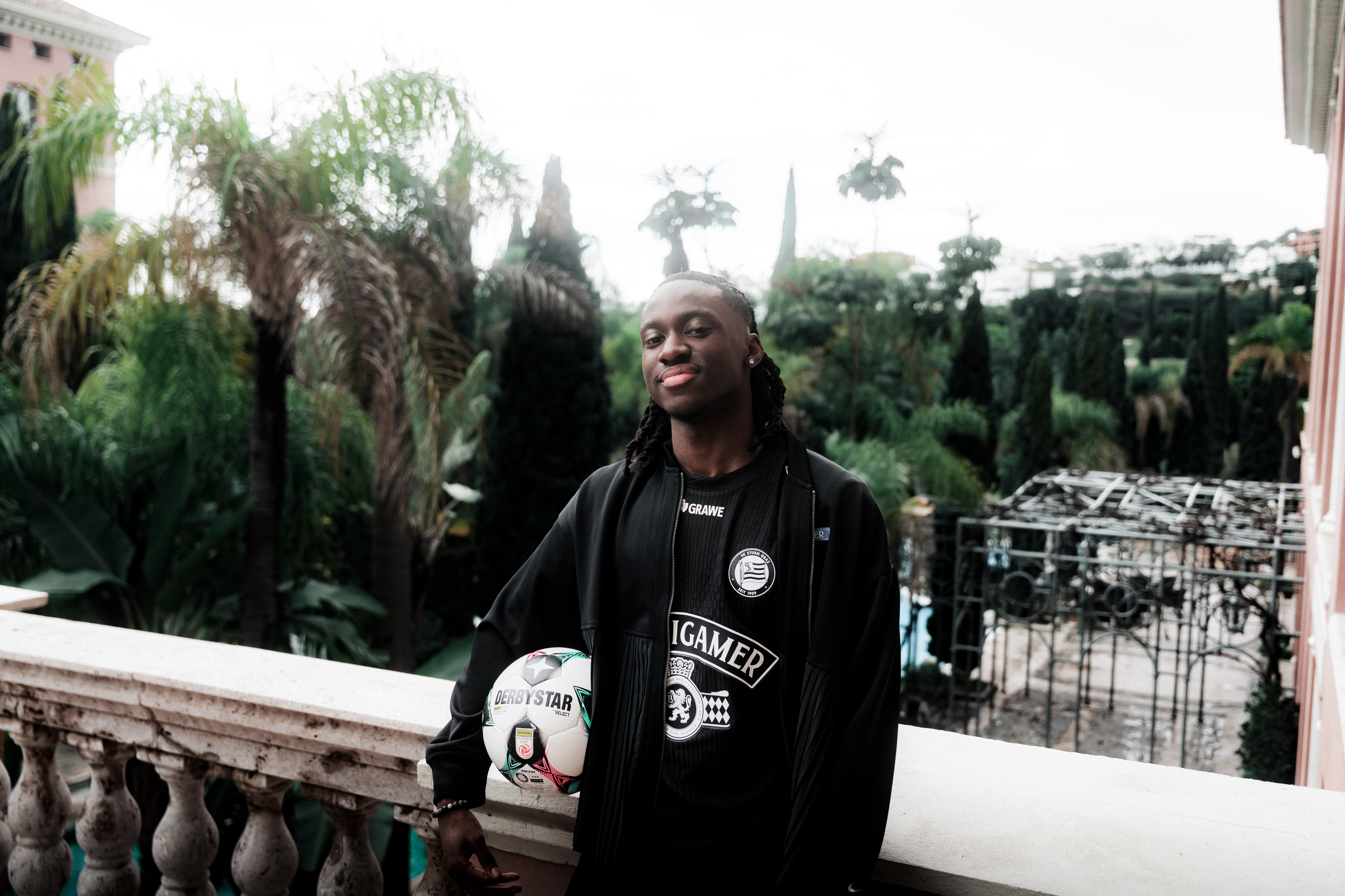 Eine Person steht mit Ball vor einer Hotelanlage