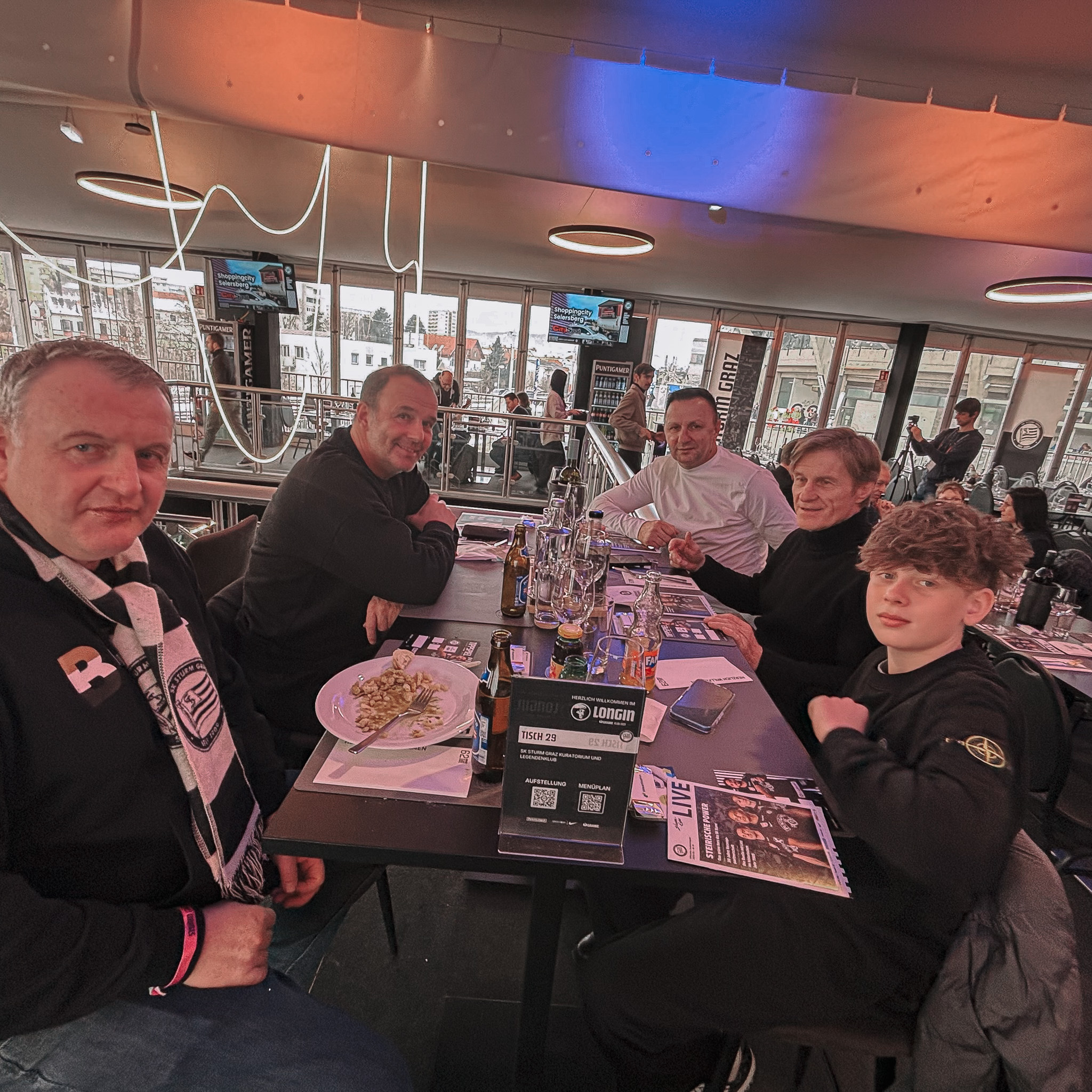 Fünf Personen sitzen an einem Hochtisch.