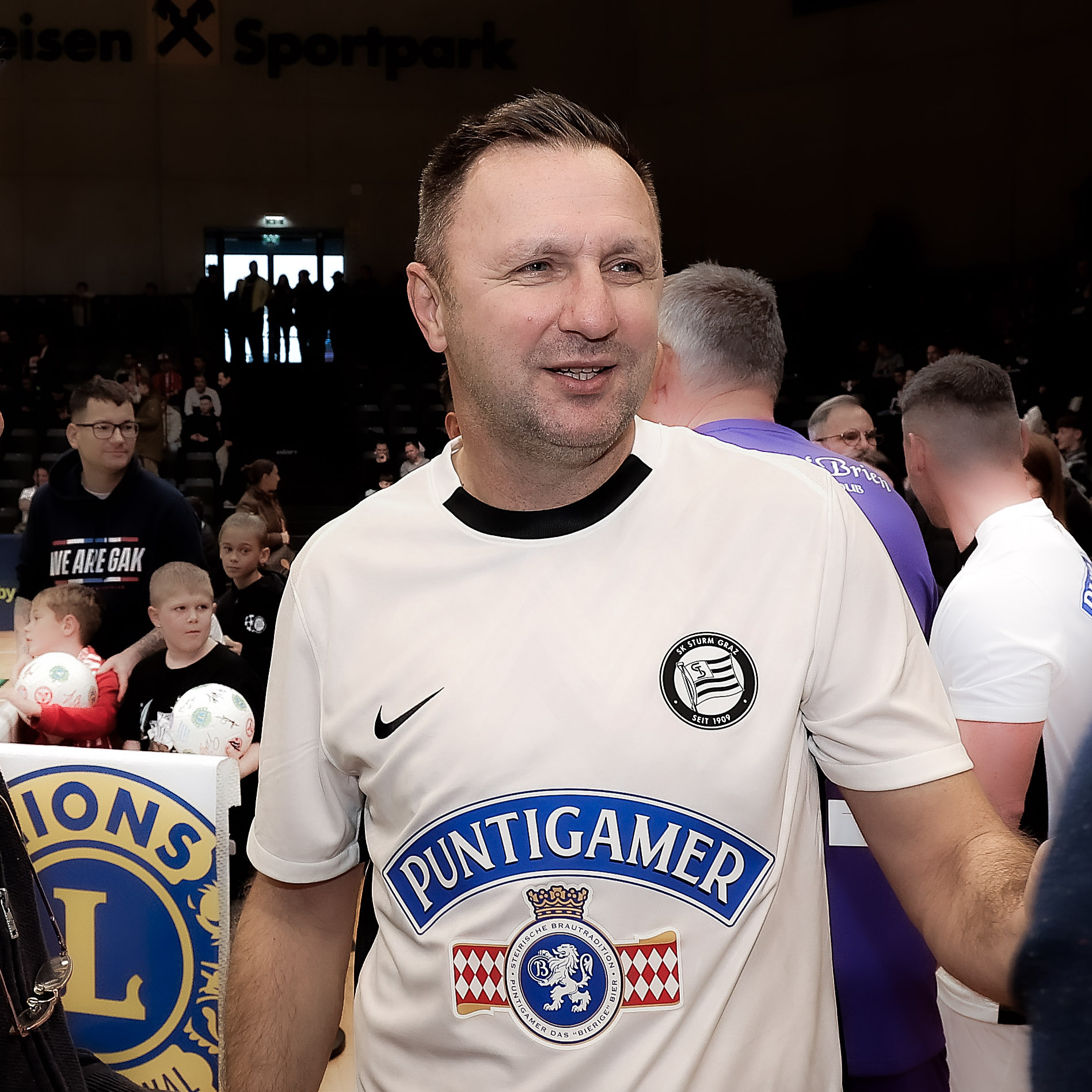 Ein Mann in einem weißen Shirt lacht.