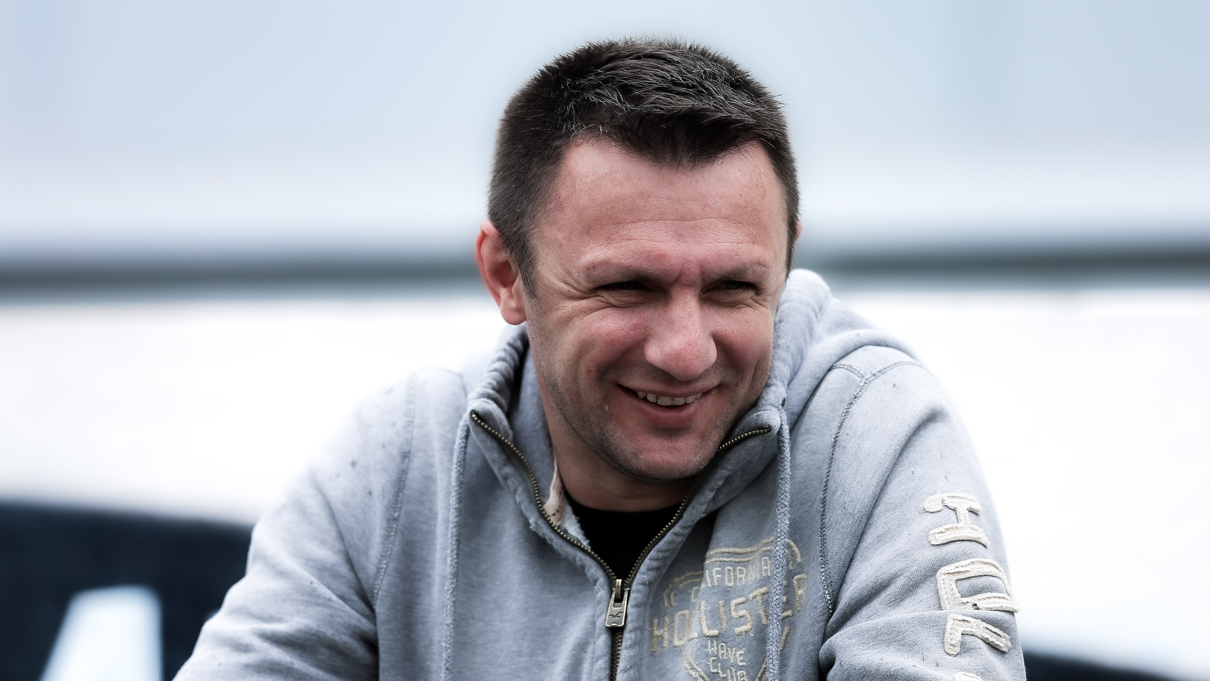 Ein Mann mit einer grauen Weste sitzt und lacht