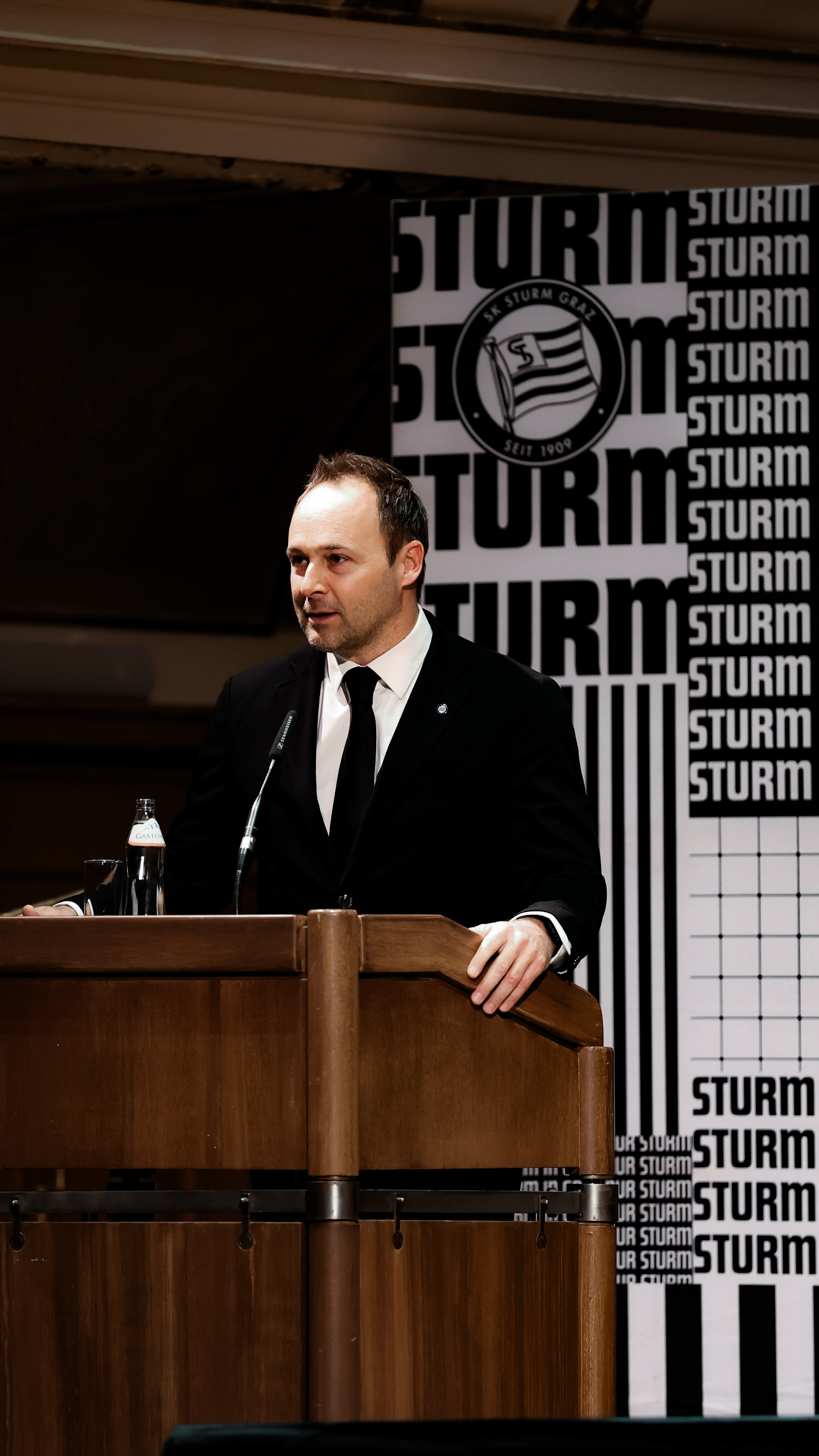 Ein Mann hinter einem Pult mit Mikro.