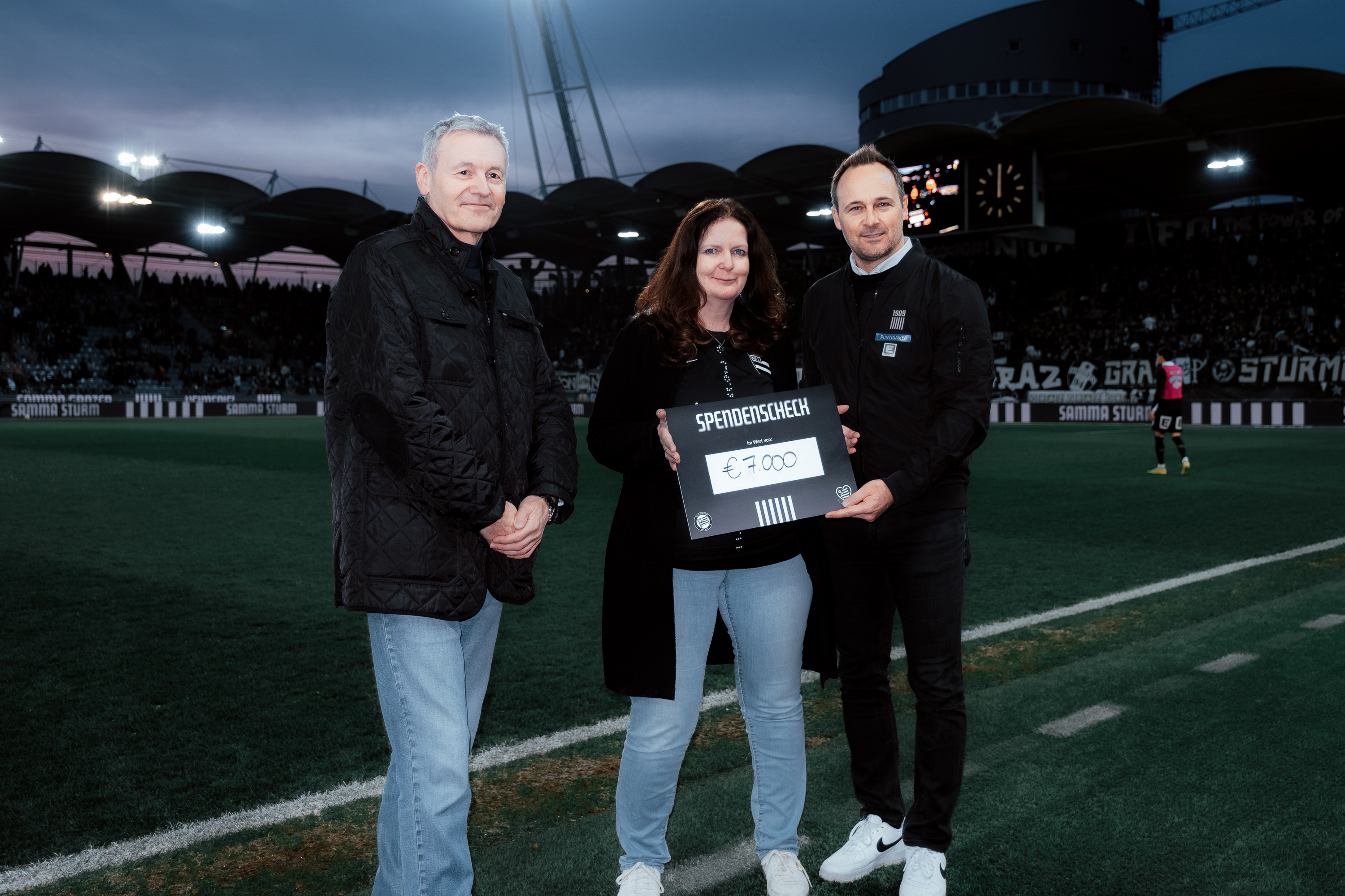 Drei Menschen mit einem Scheck.