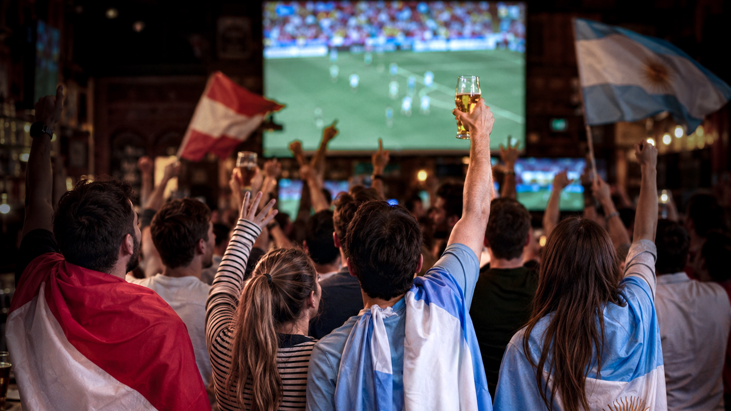 Fans mit Fahnen und Getränken vor einem Bildschirm.