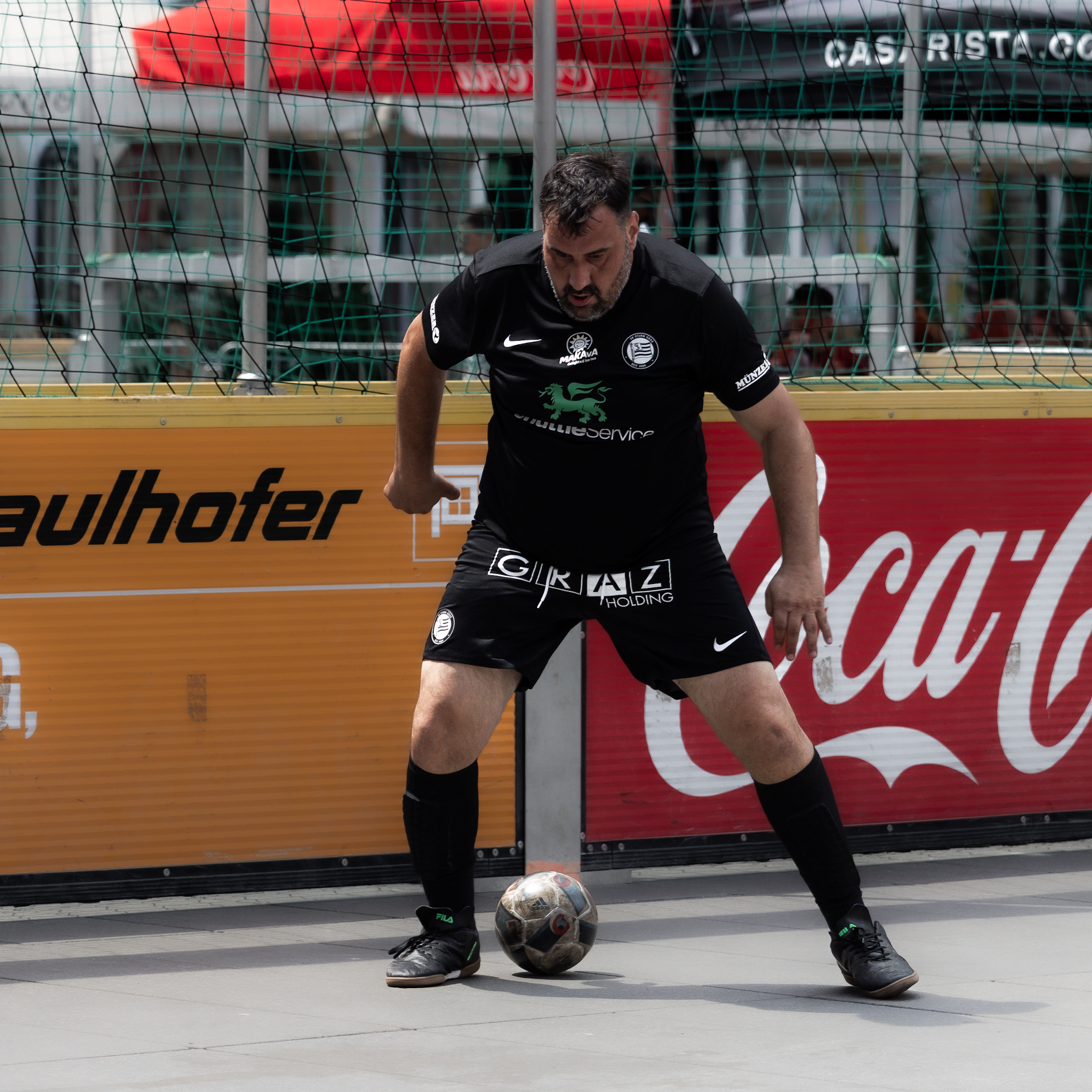 Ein Spieler in einem schwarzen Trikot und schwarzer Hose führt einen Ball.