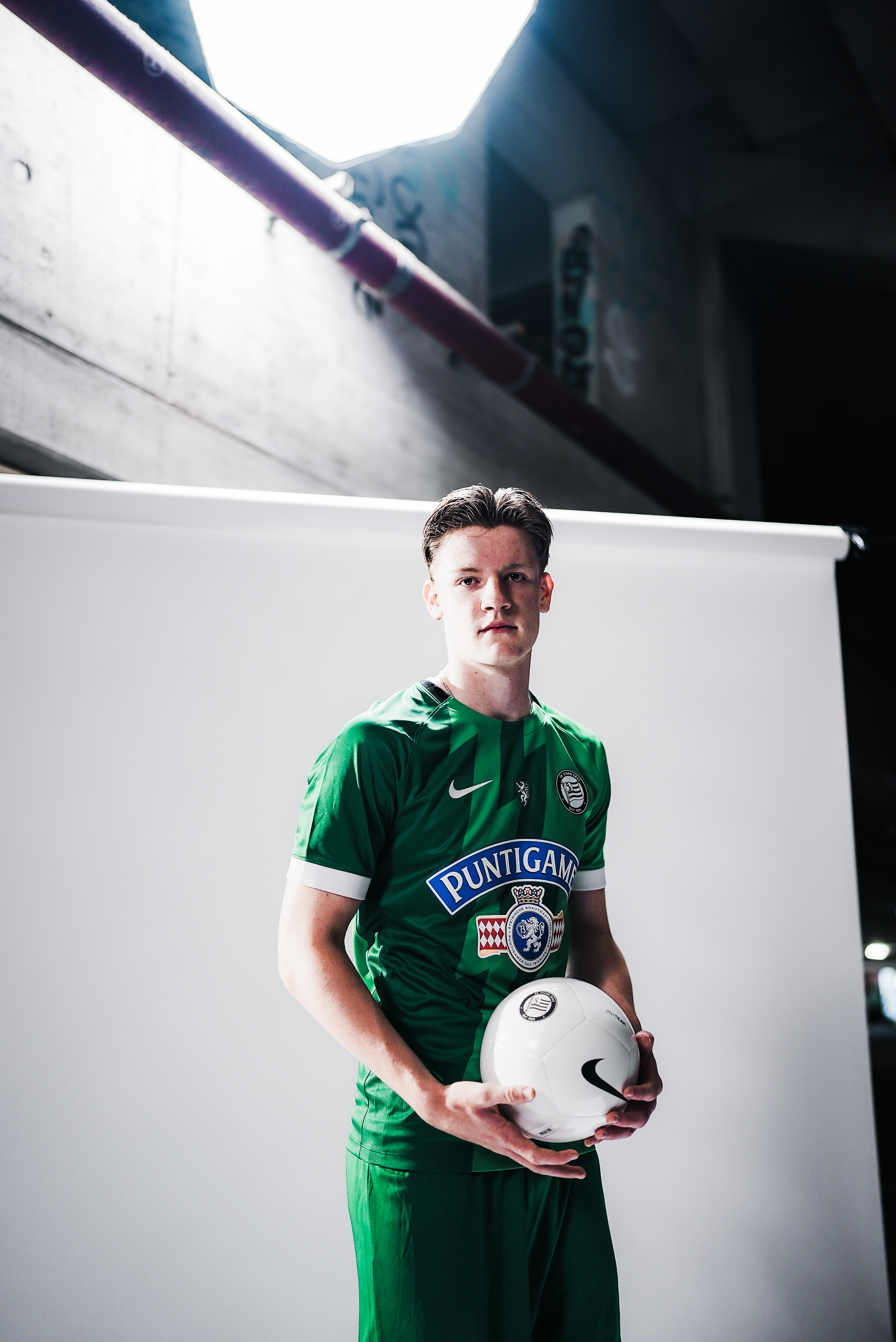 Ein Mann in einem grünen Trikot hält einen Ball.