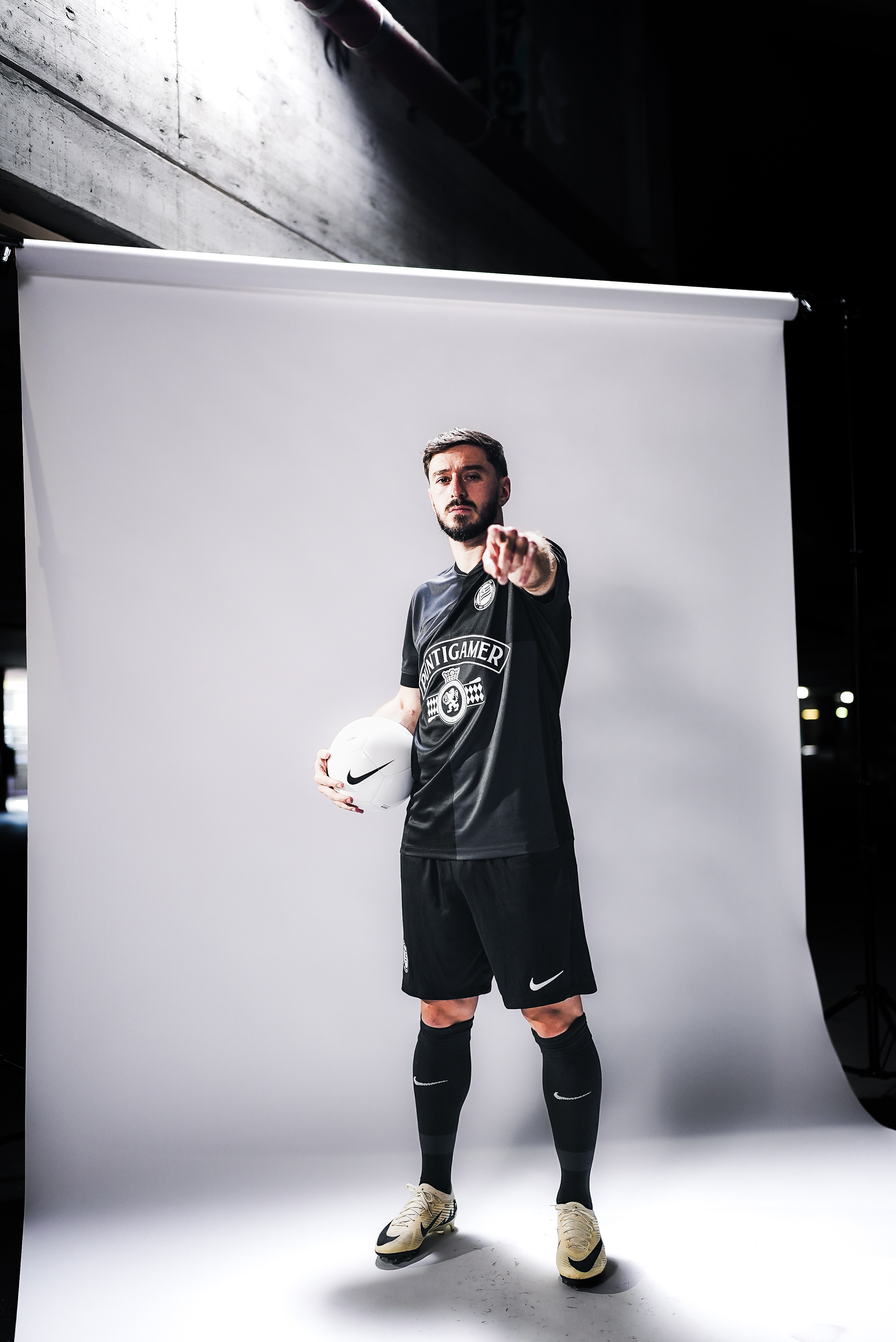 Ein Mann hält einen Ball und zeigt in die Kamera.