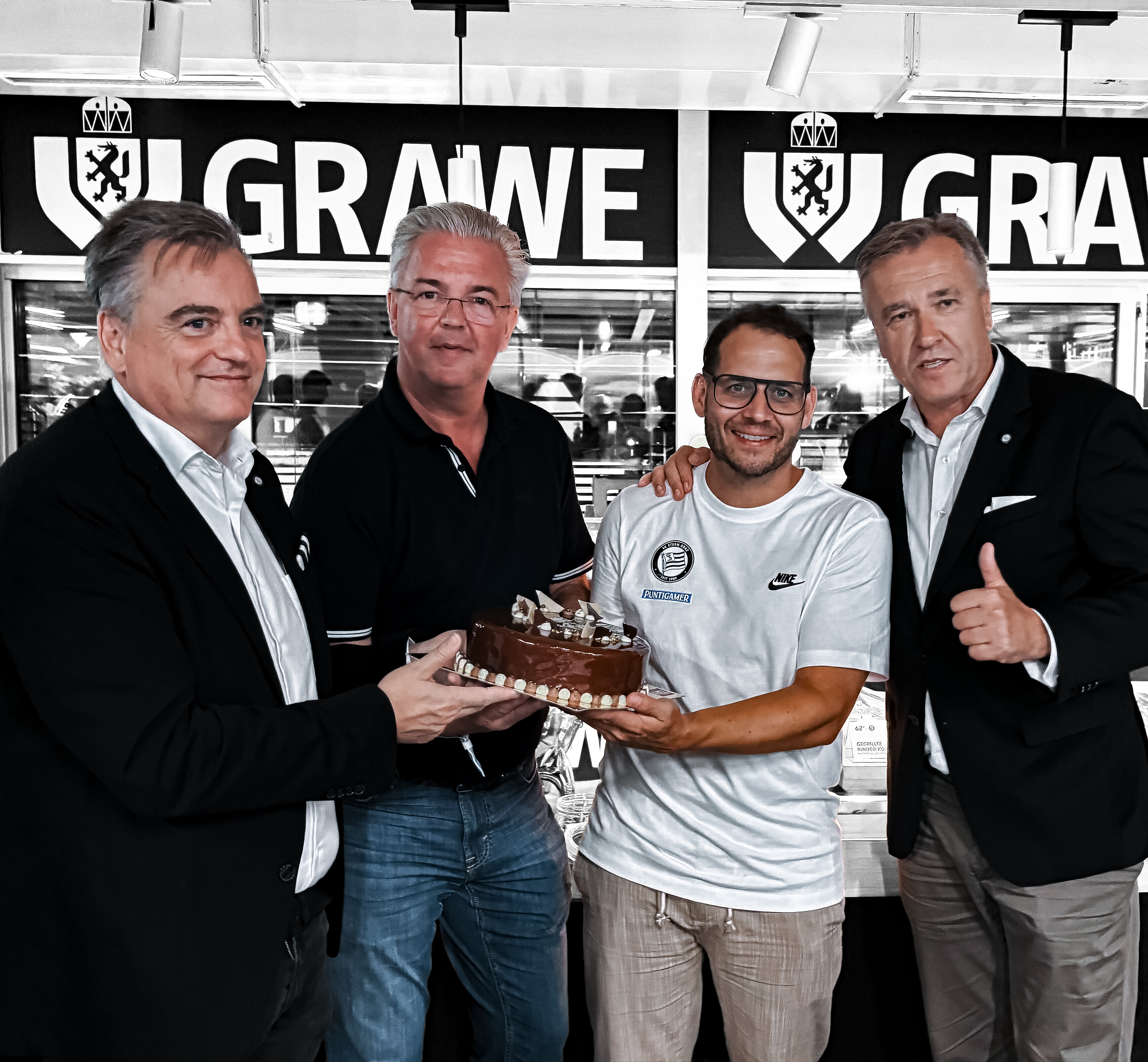 Vier Männer mit einer Torte im GRAWE VIP Klub.