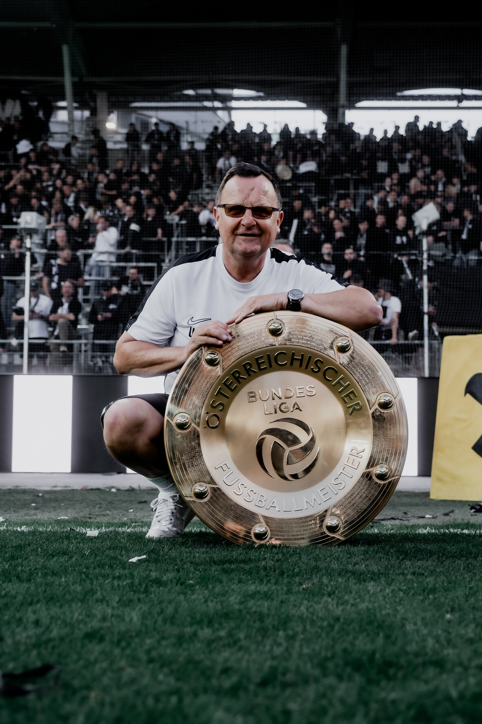 Eine Person jubelt mit einer Trophäe im Stadion