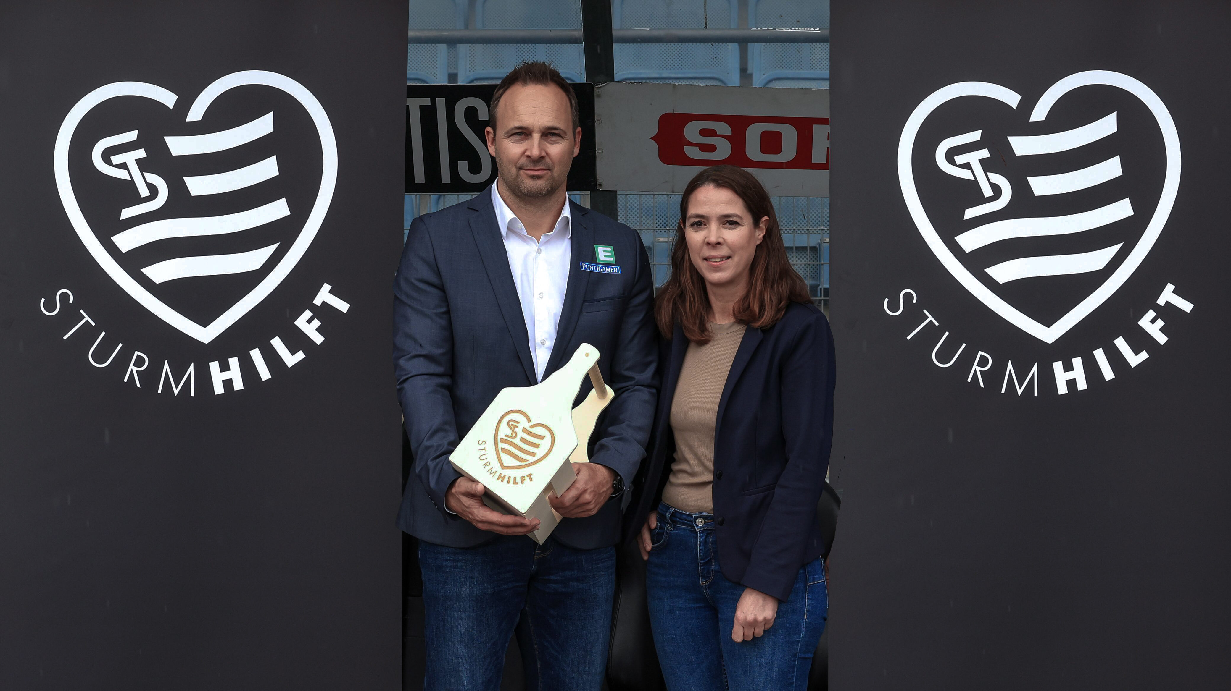 Ein Mann und eine Frau stehen vor zwei Banner.