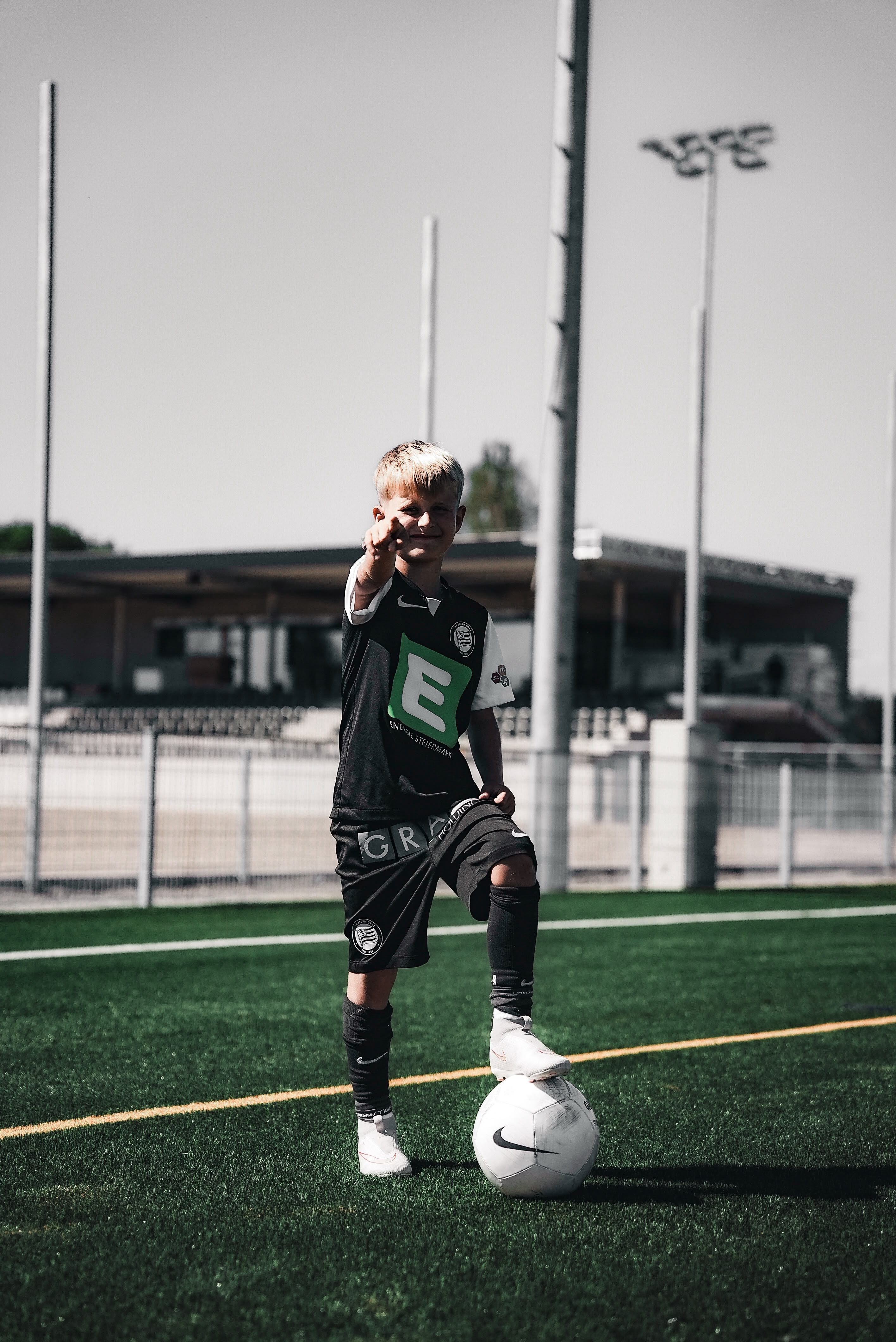 ein Junge mit Ball am Rasen.