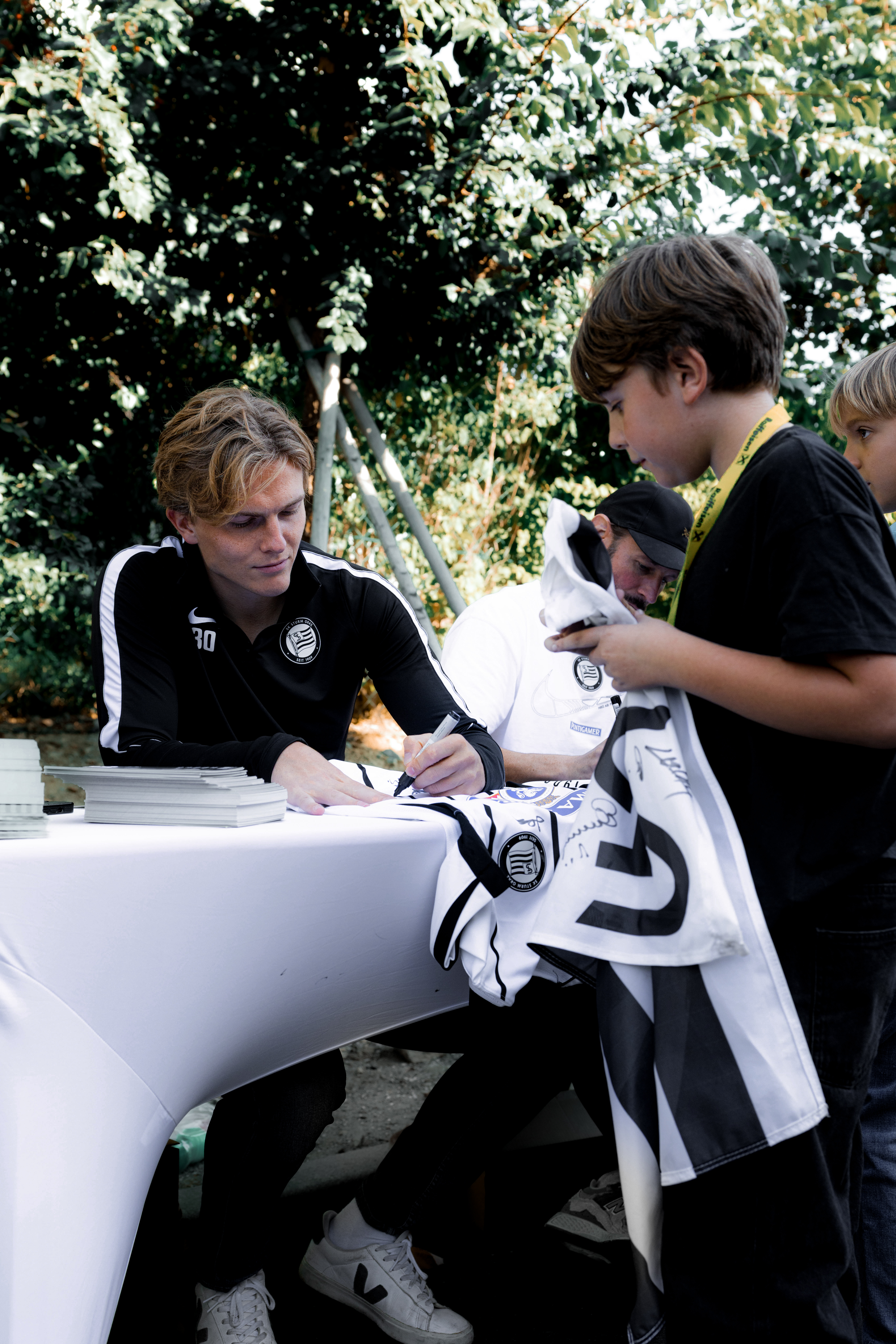 Ein Spieler unterschreibt eine Autogrammkarte.