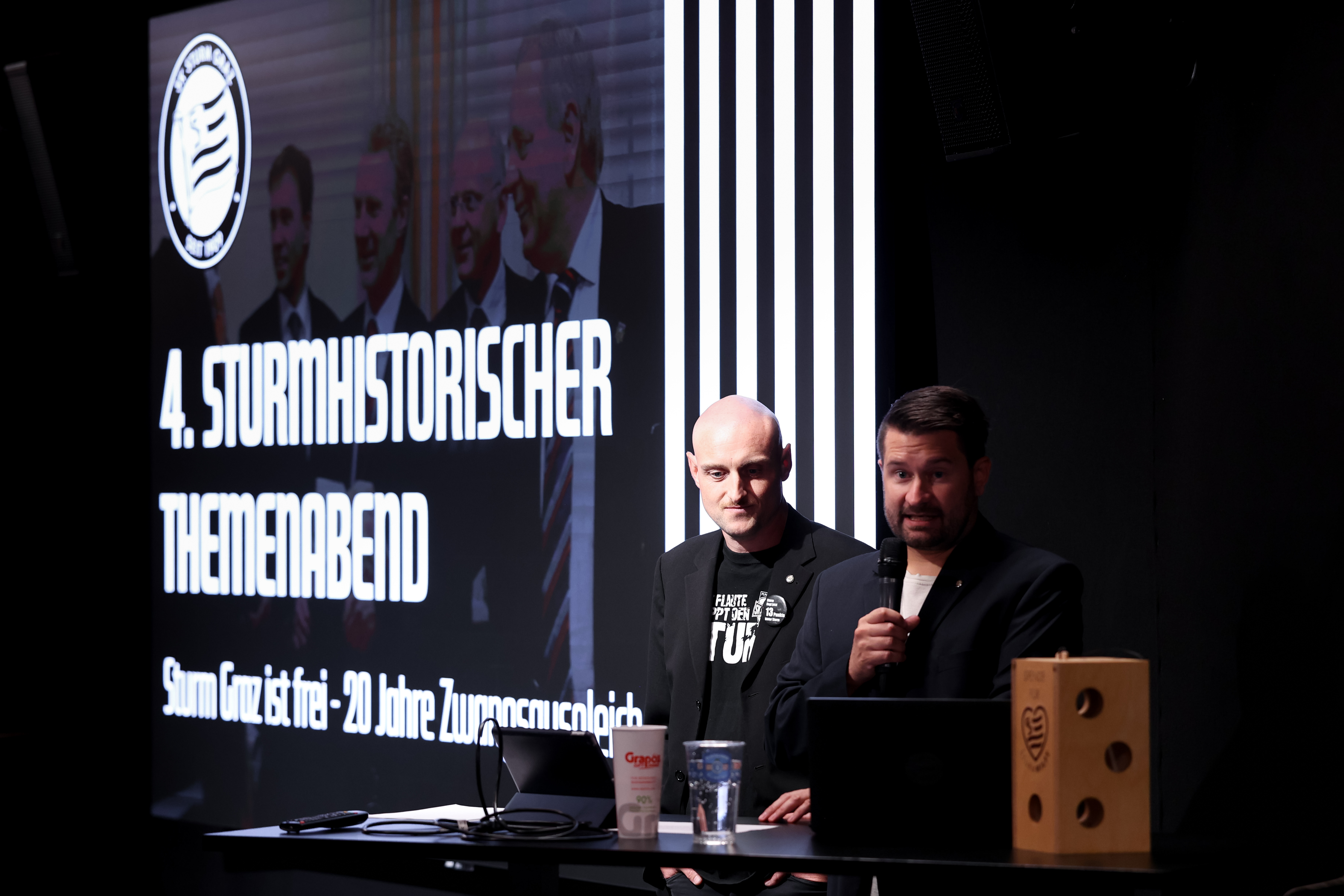 Zwei Männer vor einer Leinwand.