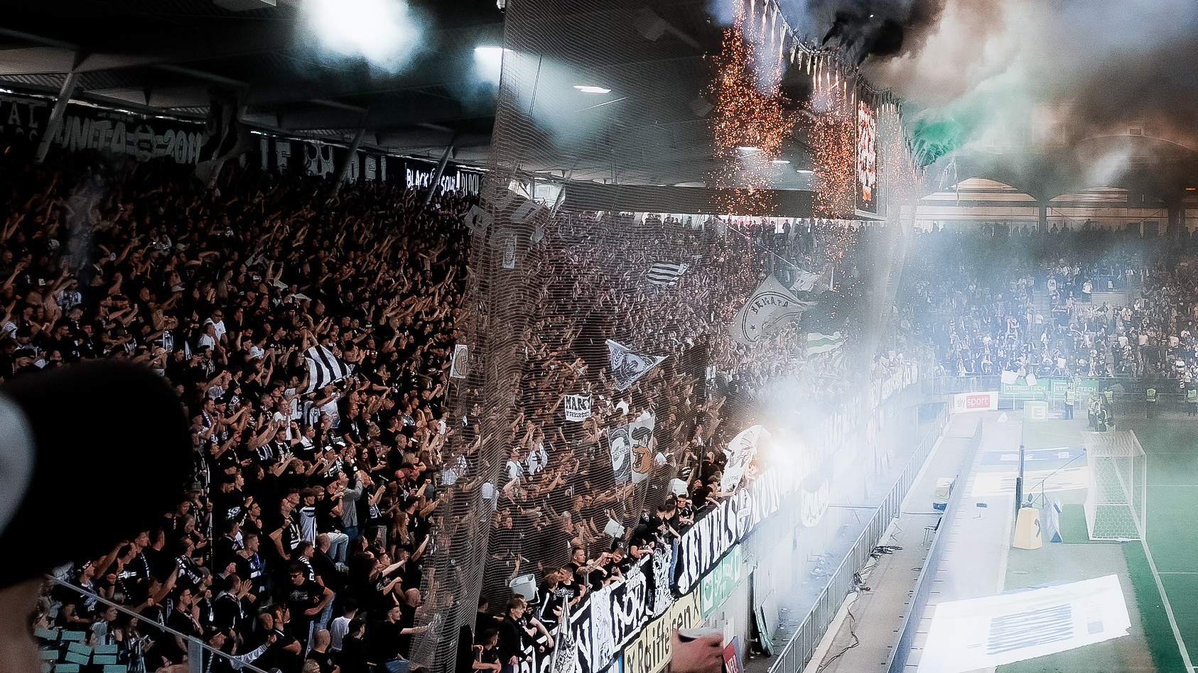 Viele Tausend Fans halten die Hände und Fahnen nach oben