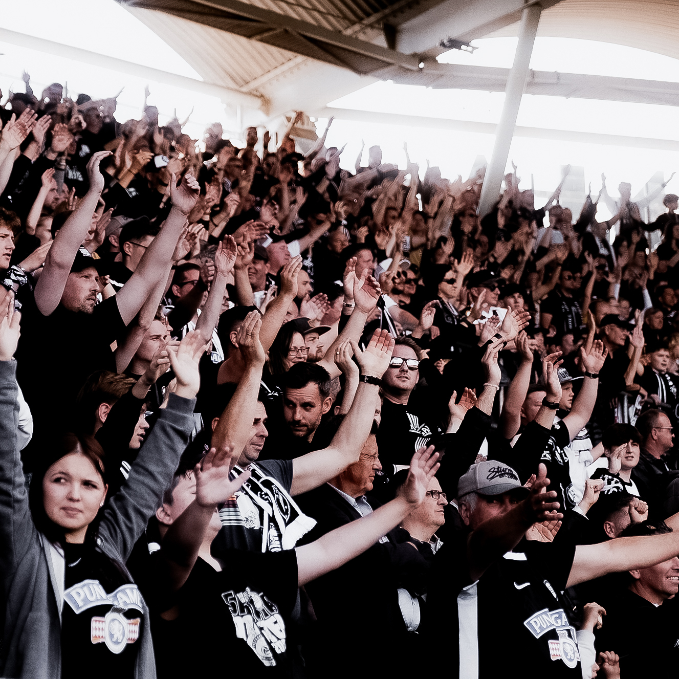Viele Menschen stehen in einem Stadion und halten ihre Hände in die Höhe