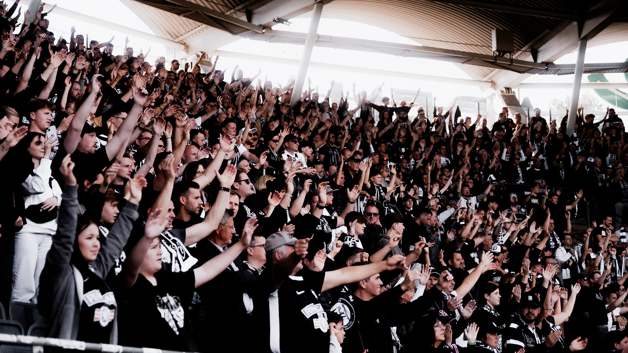 Hunderte Menschen halten in einem Stadion die Hände in die Höhe.