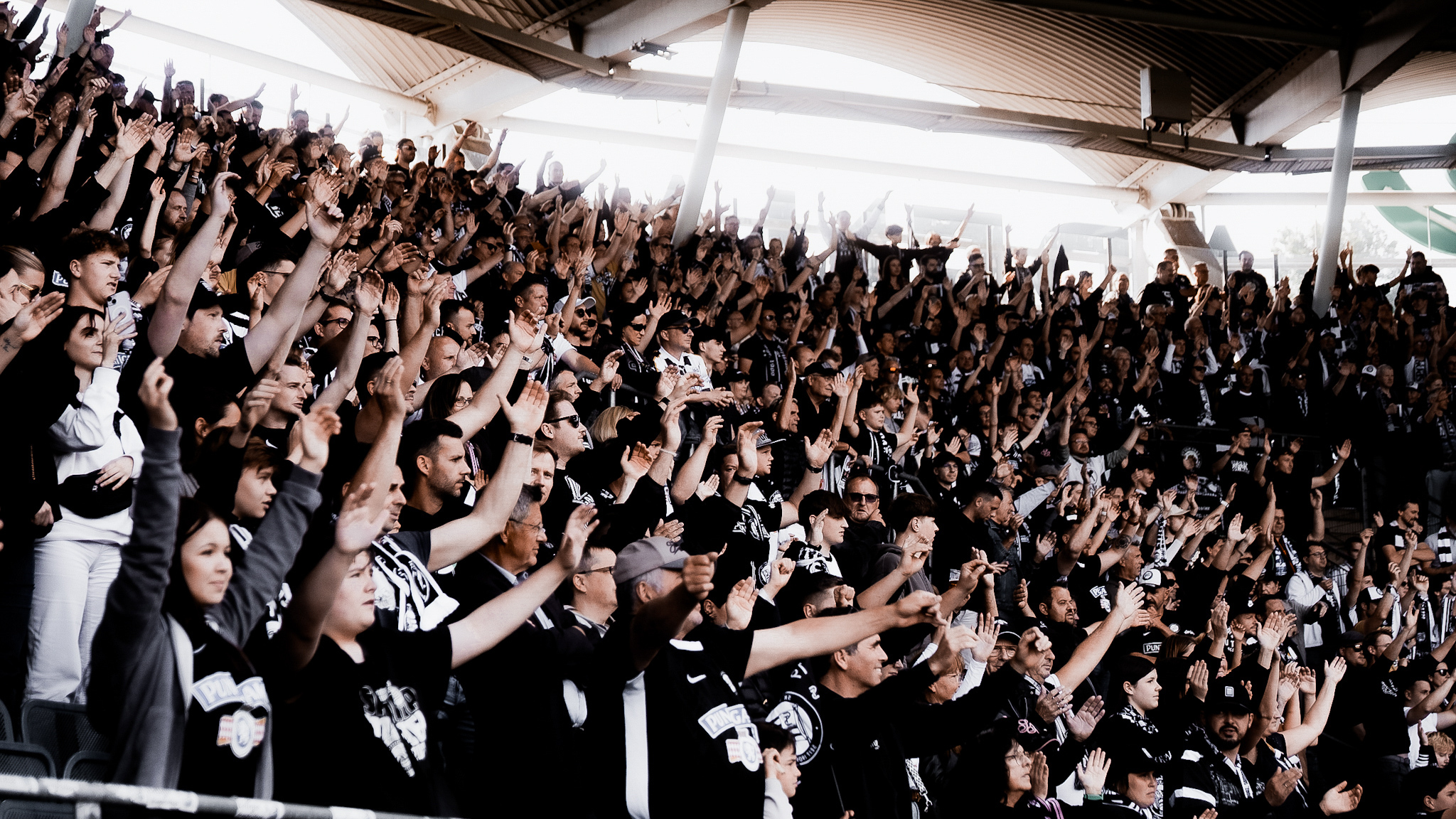 Hunderte Menschen halten in einem Stadion die Hände in die Höhe.