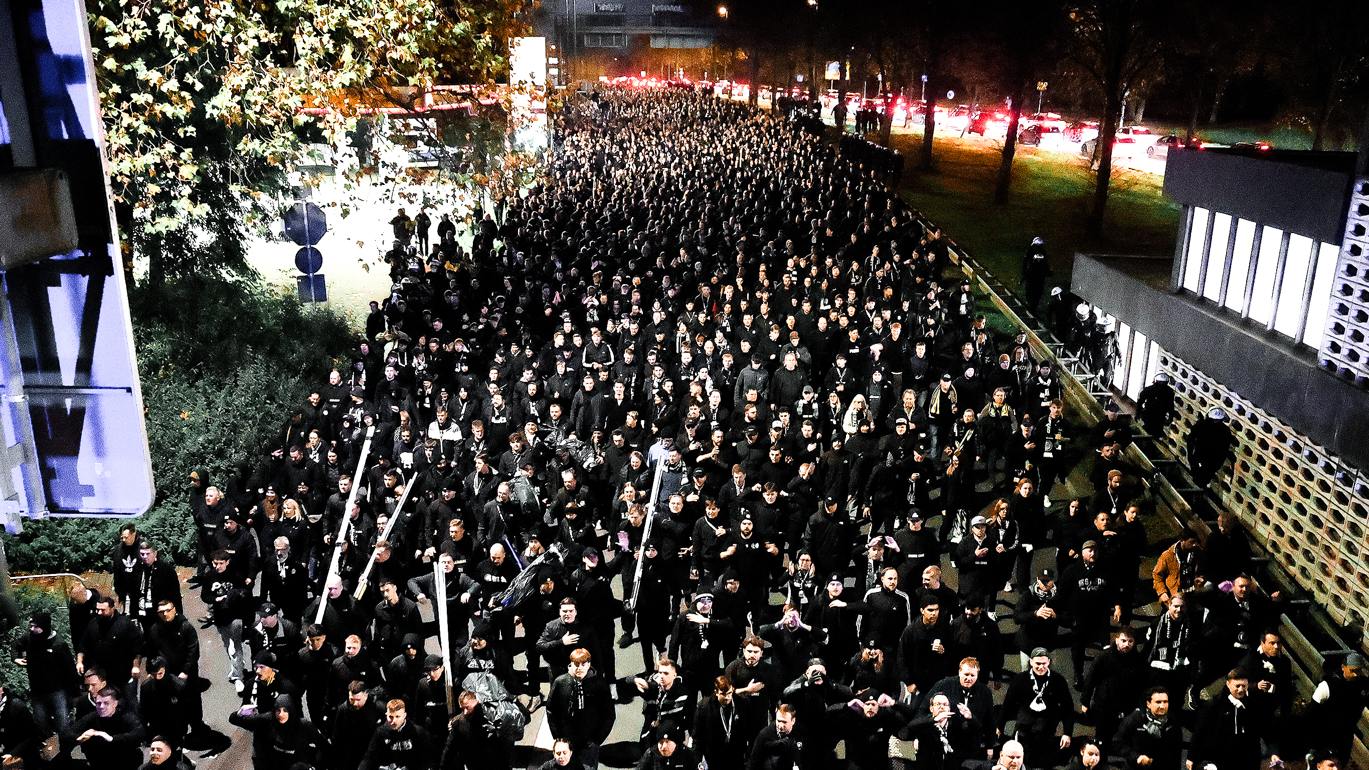 Viele Menschen in schwarz gehen auf einer Straße.