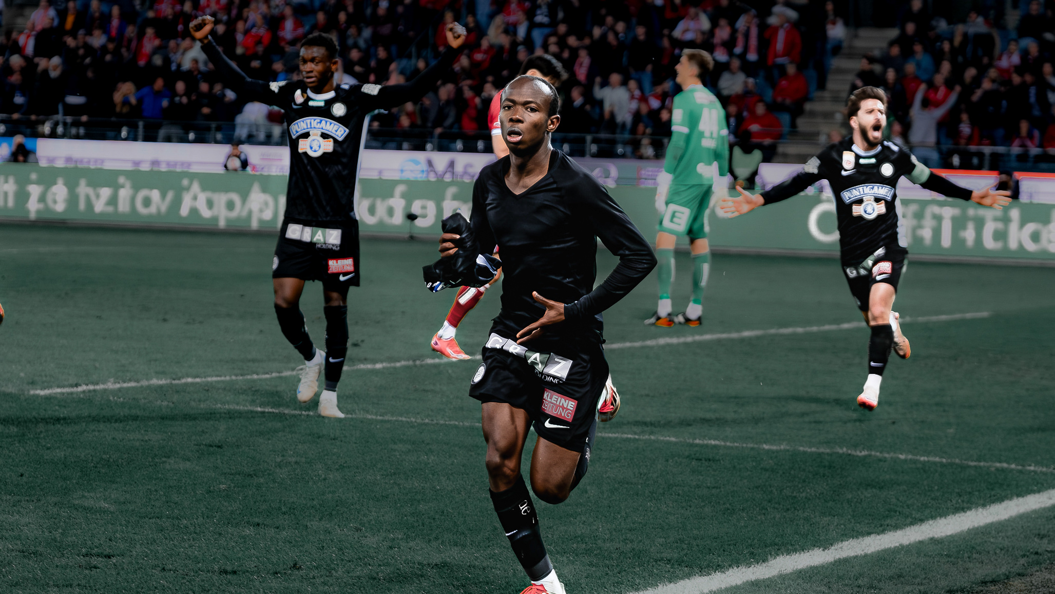 Ein Spieler ohne Trikot und zwei dahinter, die alle jubeln