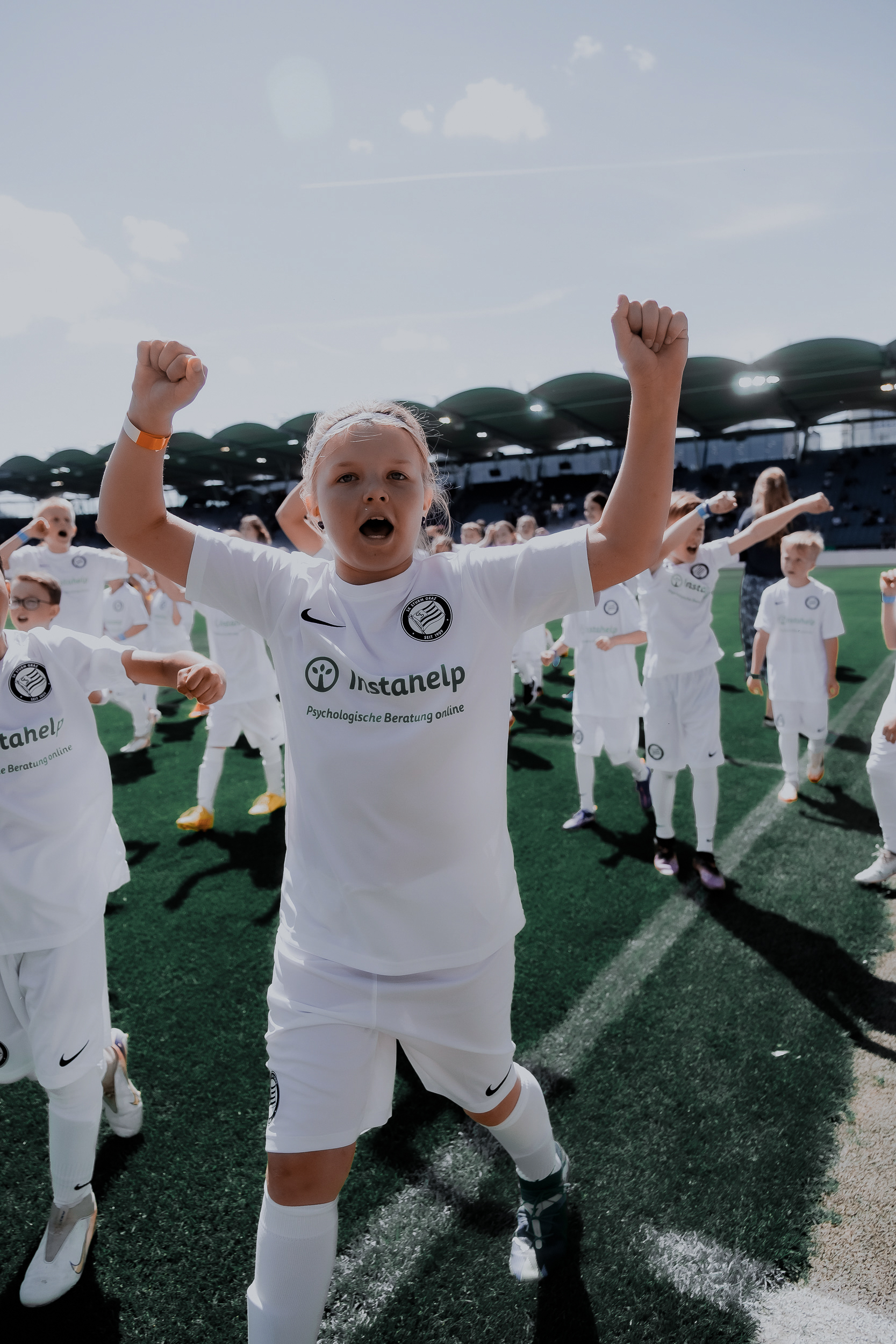 Mädchen hebt die Hände zum Jubel in die Höhe.