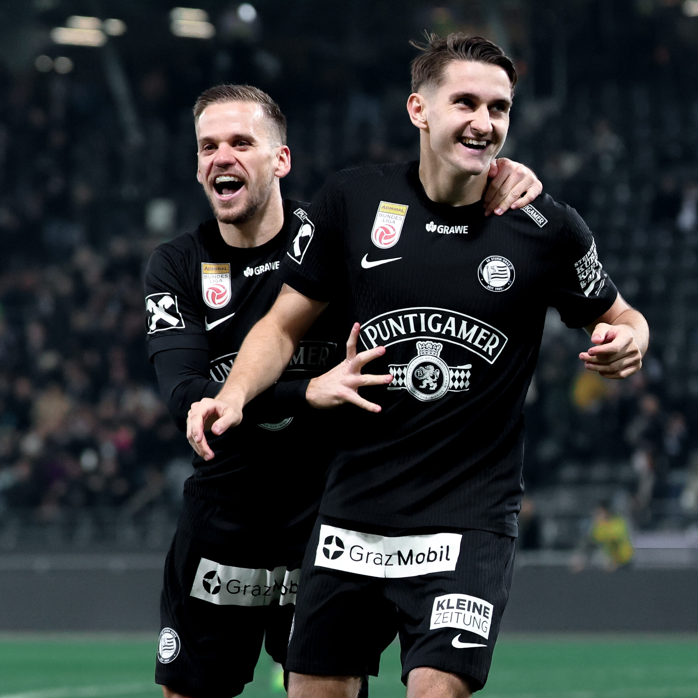 Zwei Spieler in schwarzen Trikots die jubeln