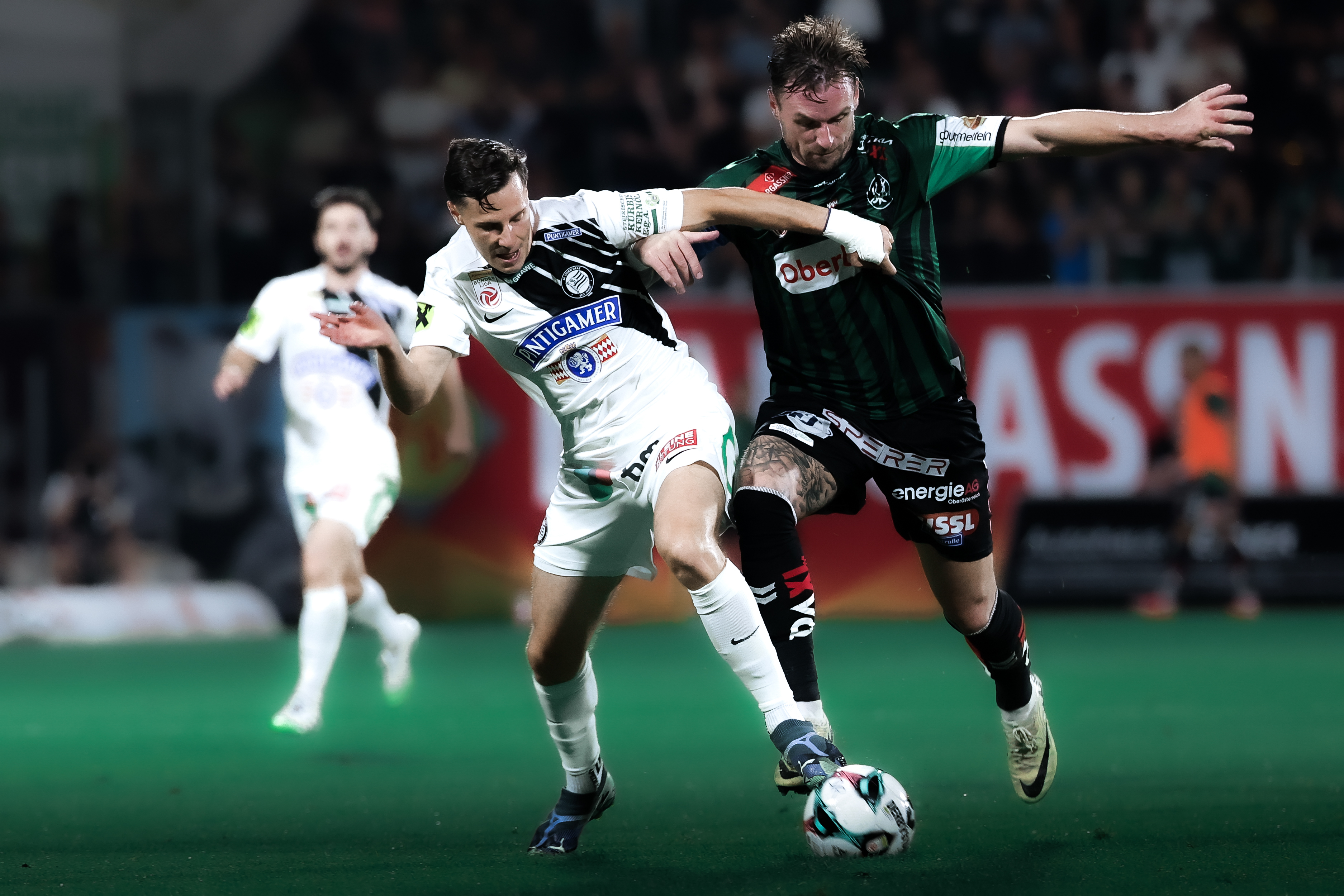 Zwei Spieler im Zweikampf um den Ball, einer in weiß und einer in grün-weiß