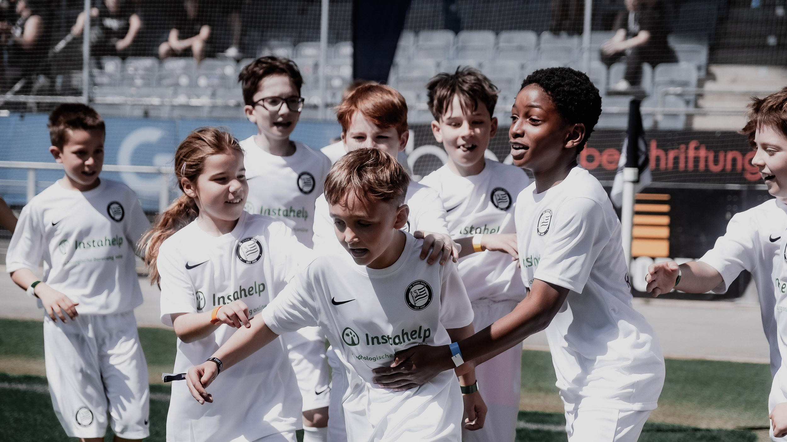 Acht Kinder in weißen Trikots lachen