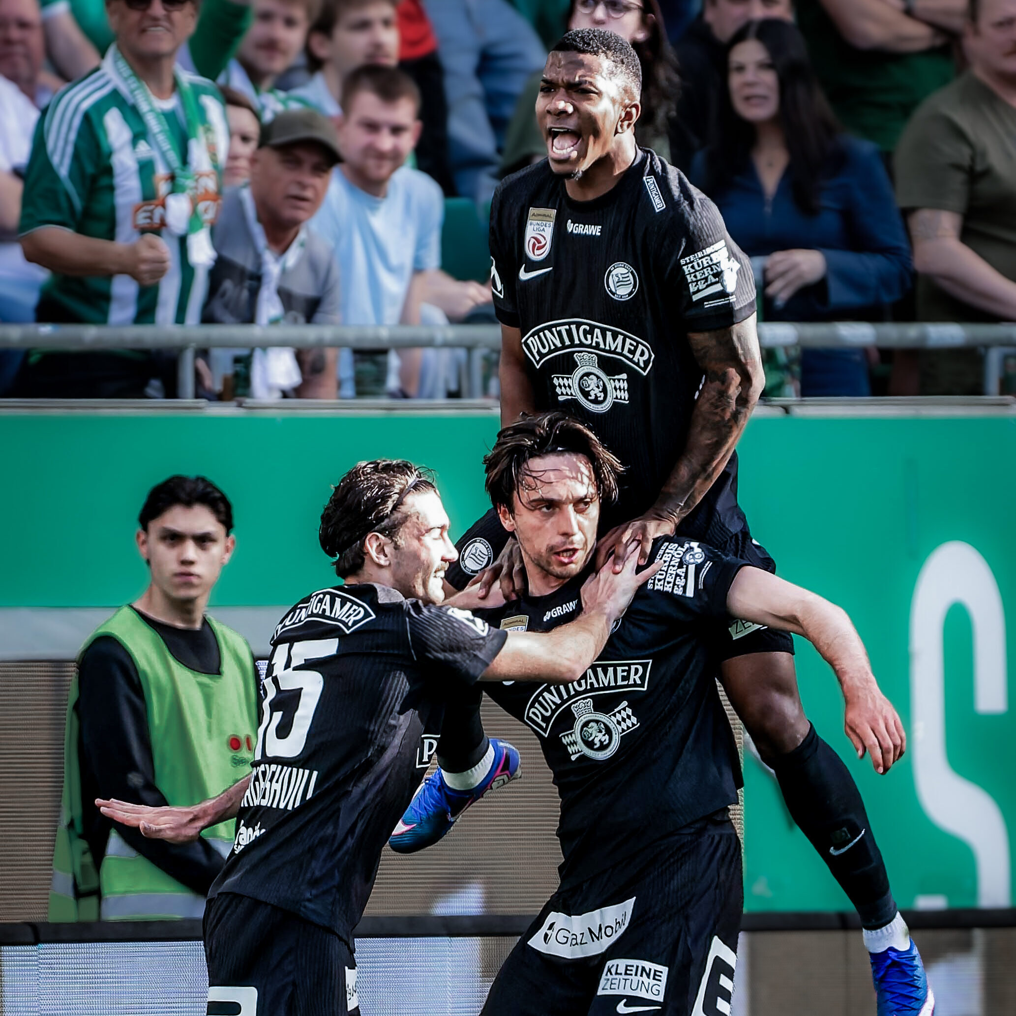 Drei Spieler in schwarz gekleidet jubeln