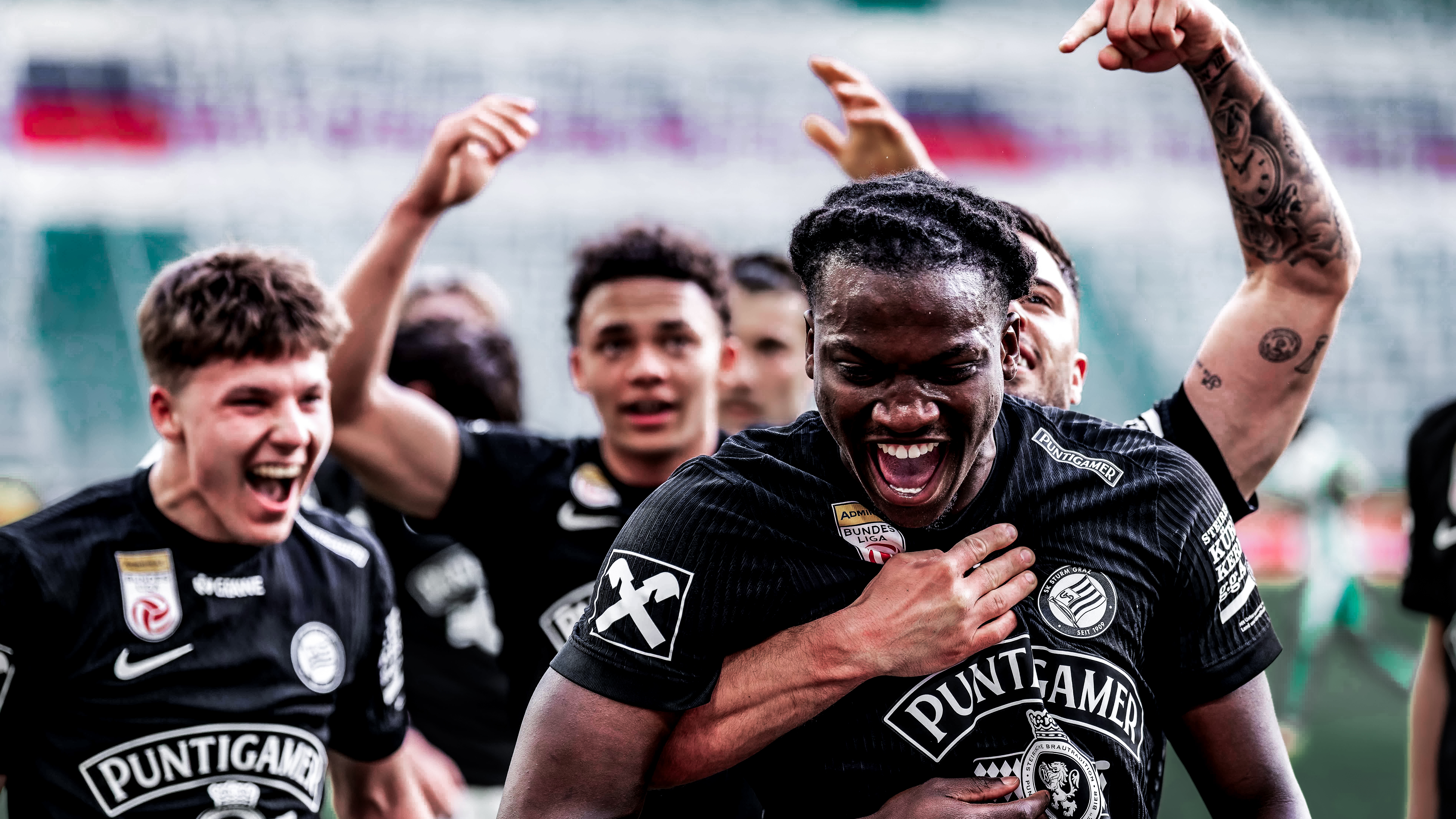 Mehrere Spieler in schwarzen Trikots jubeln