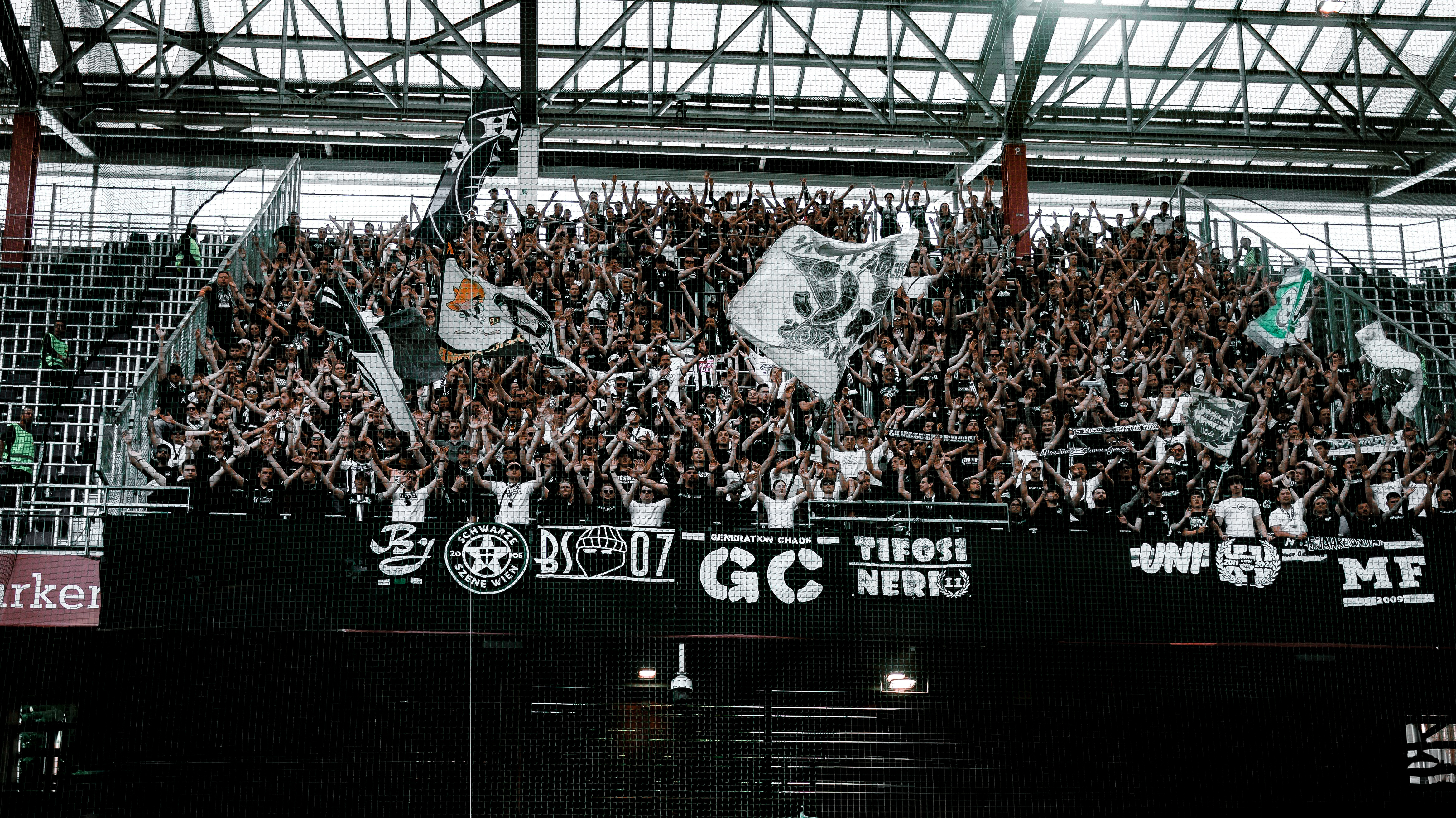 Drei Spieler stehen vor vielen Fans und haben die Hände in der Luft.