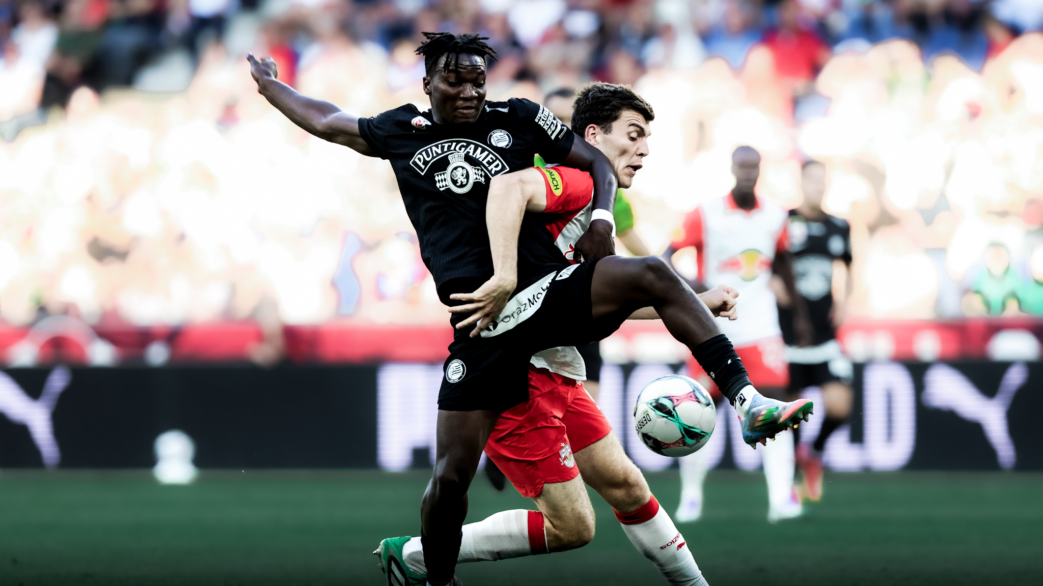 Ein Spieler in schwarz kämpft mit einem Spieler in weiß um einen weißen Ball