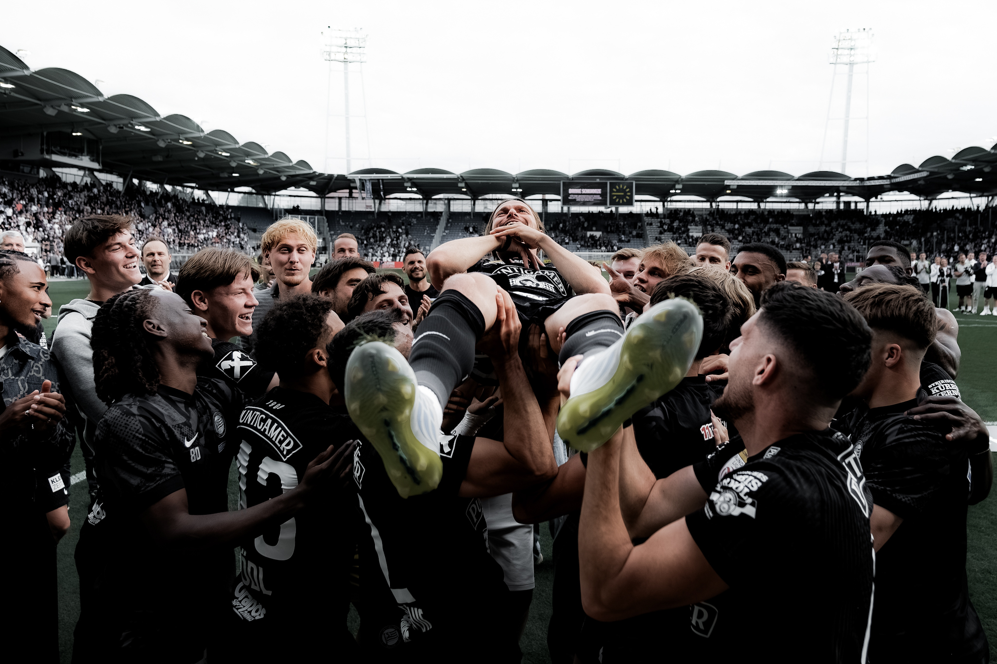 Viele Spieler in schwarz werfen einen Spieler in schwarz in die Luft