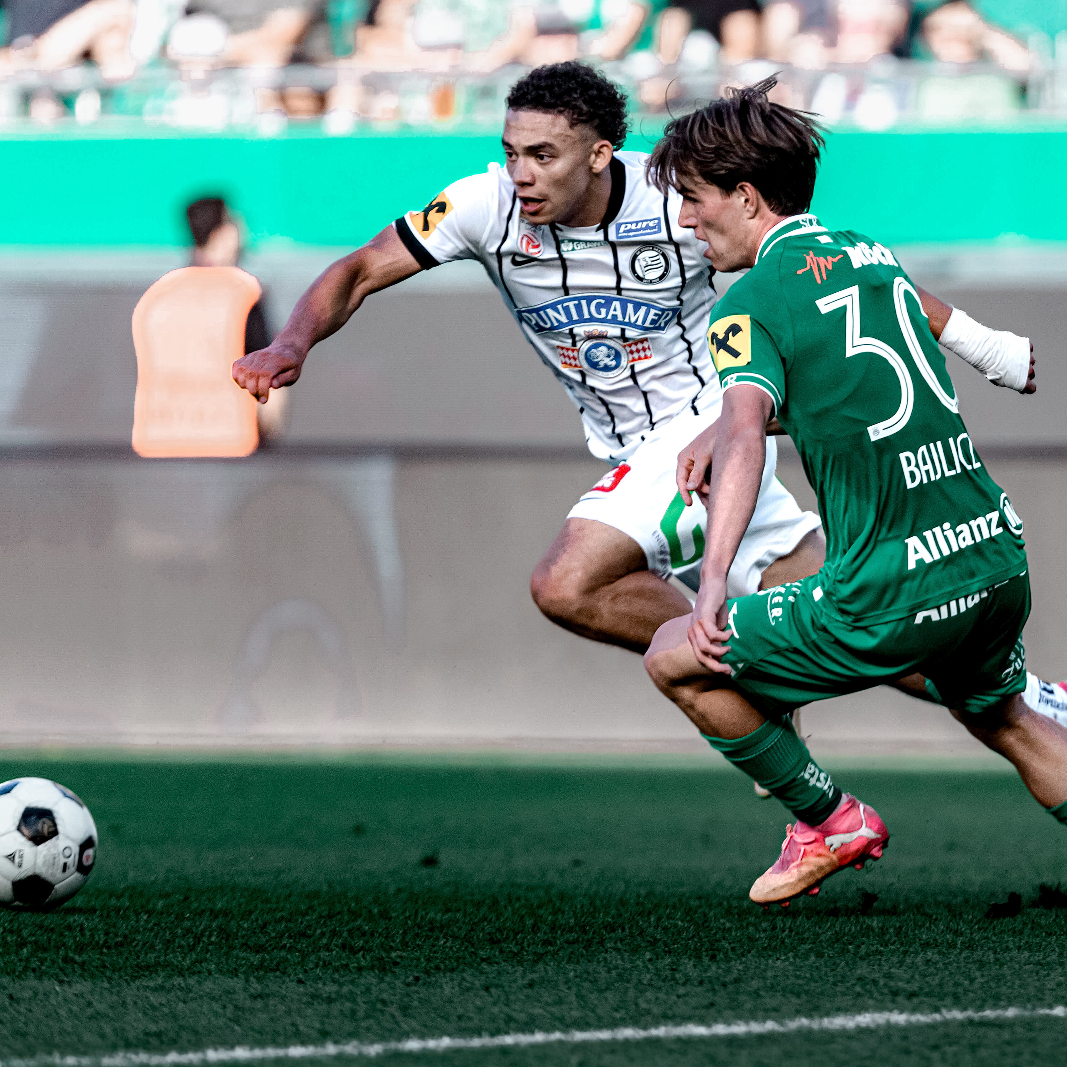 Ein Spieler in weiß und einer in grün kämpfen um einen weißen Ball.