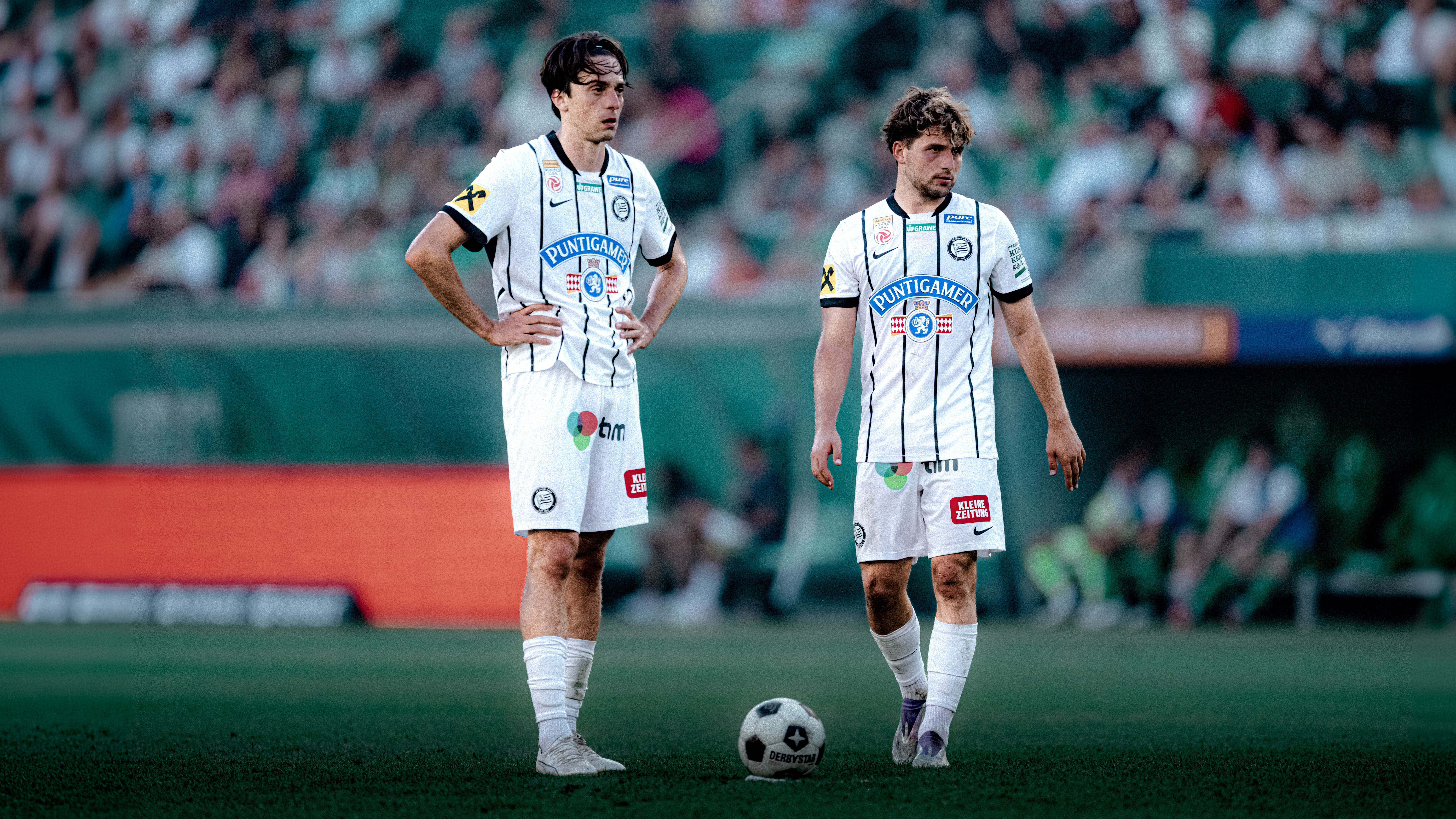 Zwei Spieler in weißen Trikots stehen und schauen in eine Richtung.